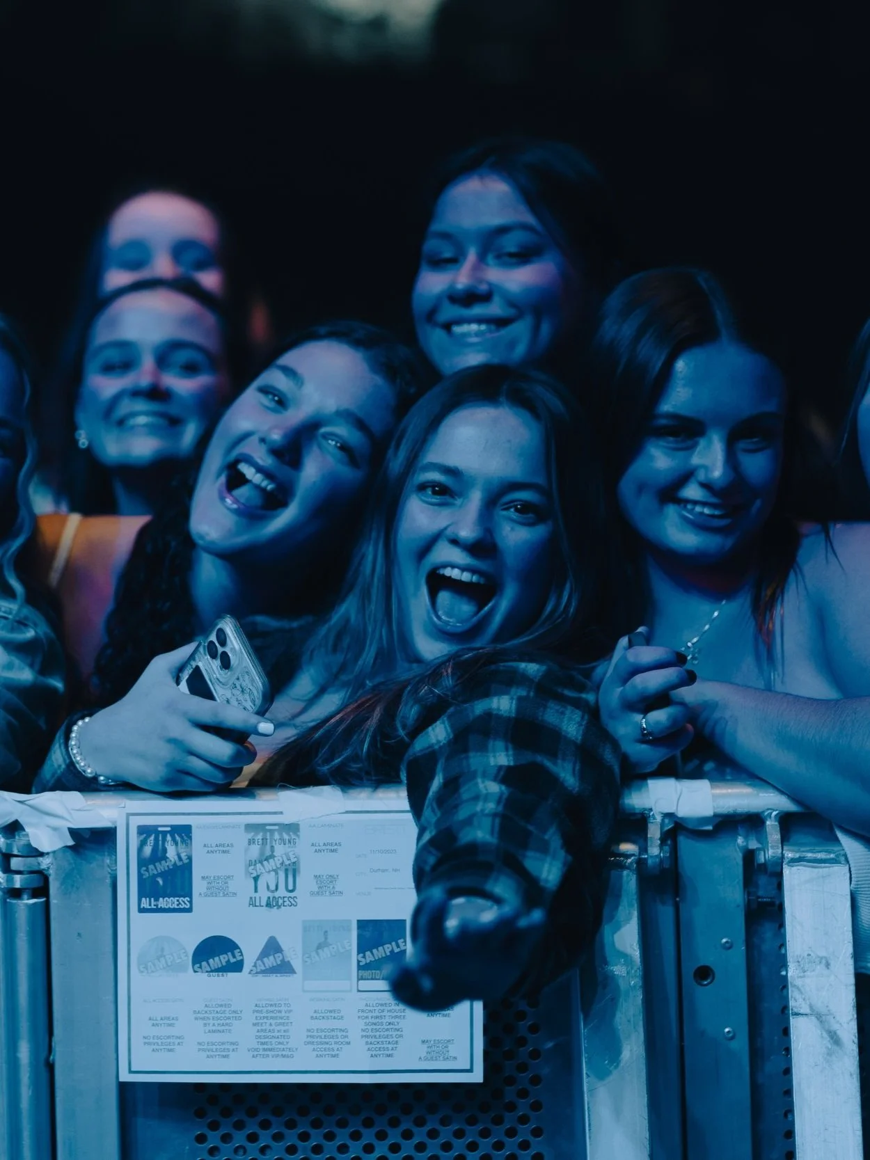 Group of young women excited and smiling at a concert or event, with a ticket in front of them.