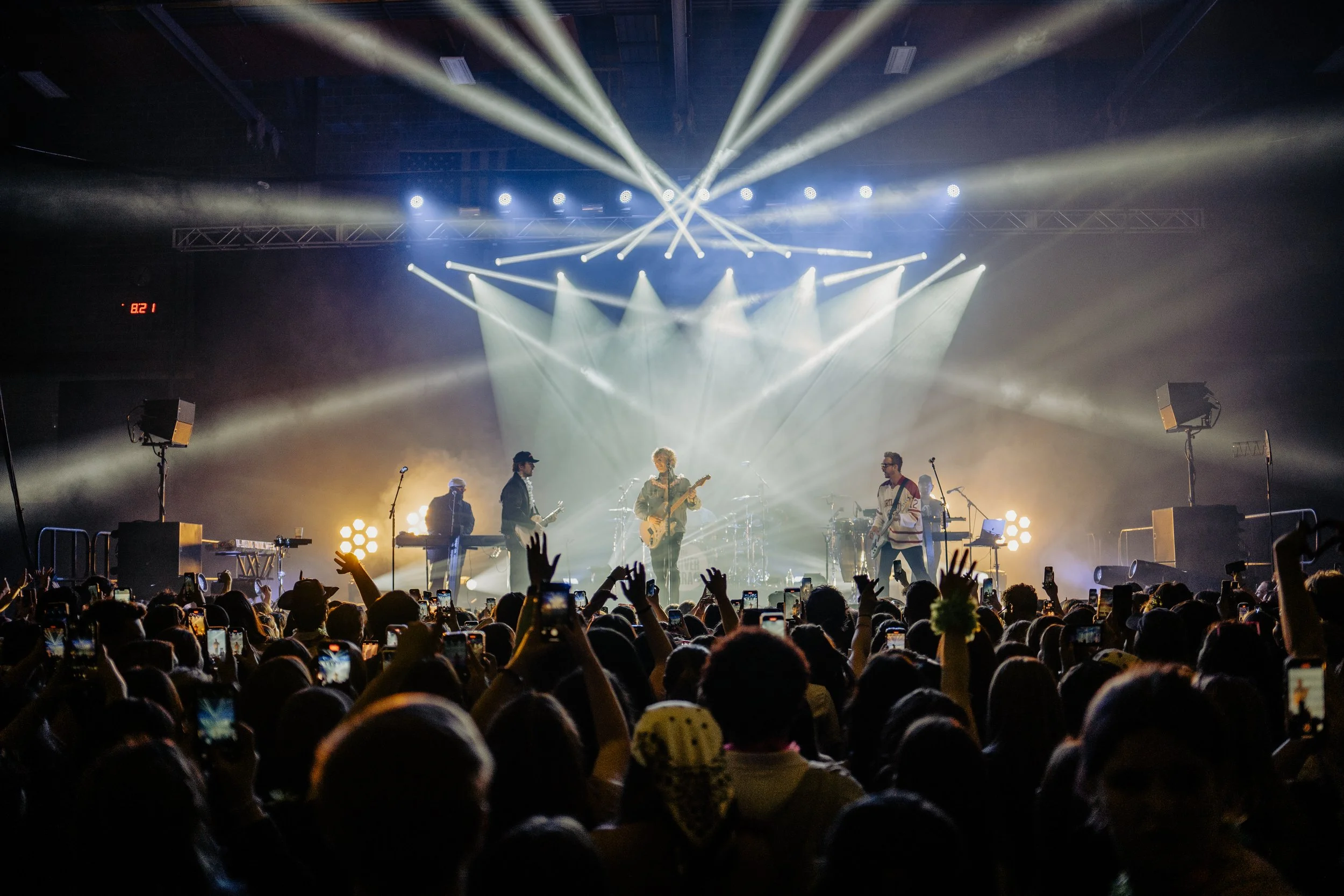 A live concert with The Driver Era on stage, performing with bright lights and fog effects, in front of an audience at night.