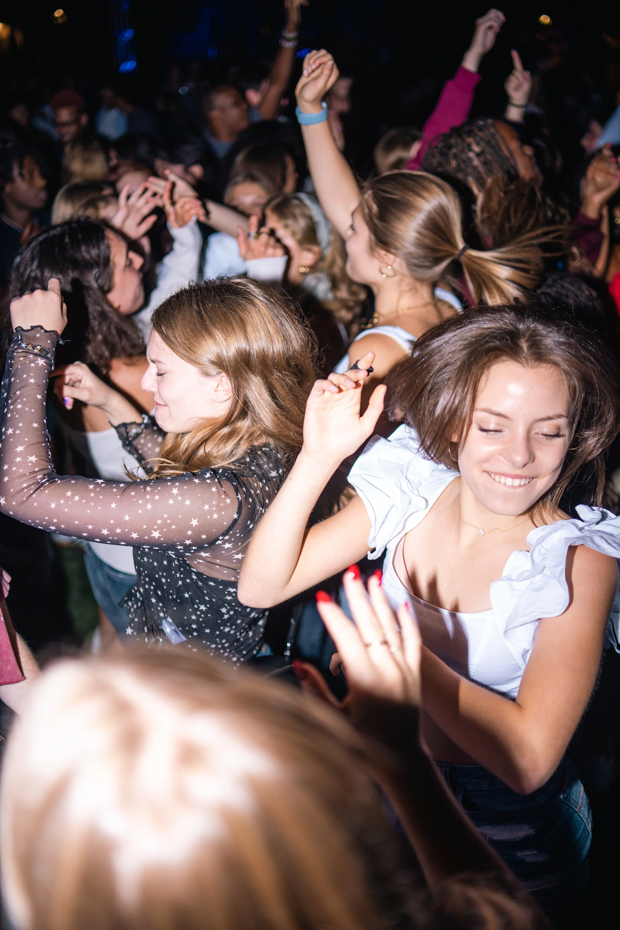 Group of young women dancing and enjoying a lively party or concert at night.