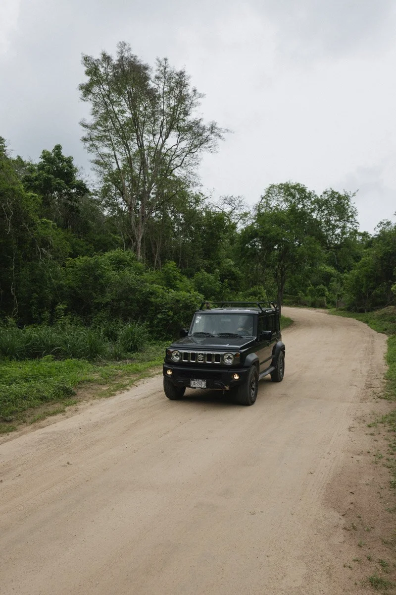 A black SUV driving on a dirt road surrounded by green trees and bushes. Travel photography by Sergio Gutiérrez sergiogutierrezphoto.