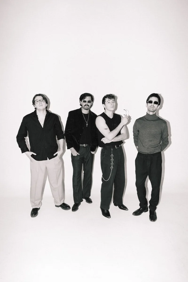 Four men standing against a plain background, dressed in dark clothing and sunglasses, posing with a casual attitude. Band group photoshoot, Real Albatross in Guadalajara, Jalisco. By Sergio Gutiérrez sergiogutierrezphoto.