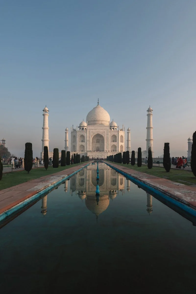 The image shows the Taj Mahal, a white marble mausoleum in India, with its reflection in the water in front of it during daytime. Travel photograhy by Sergio Gutiérrez sergiogutierrezphoto.
