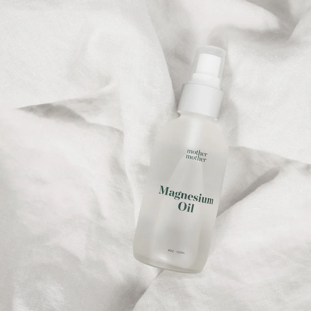 A bottle of Mother Mother magnesium oil resting on white linen