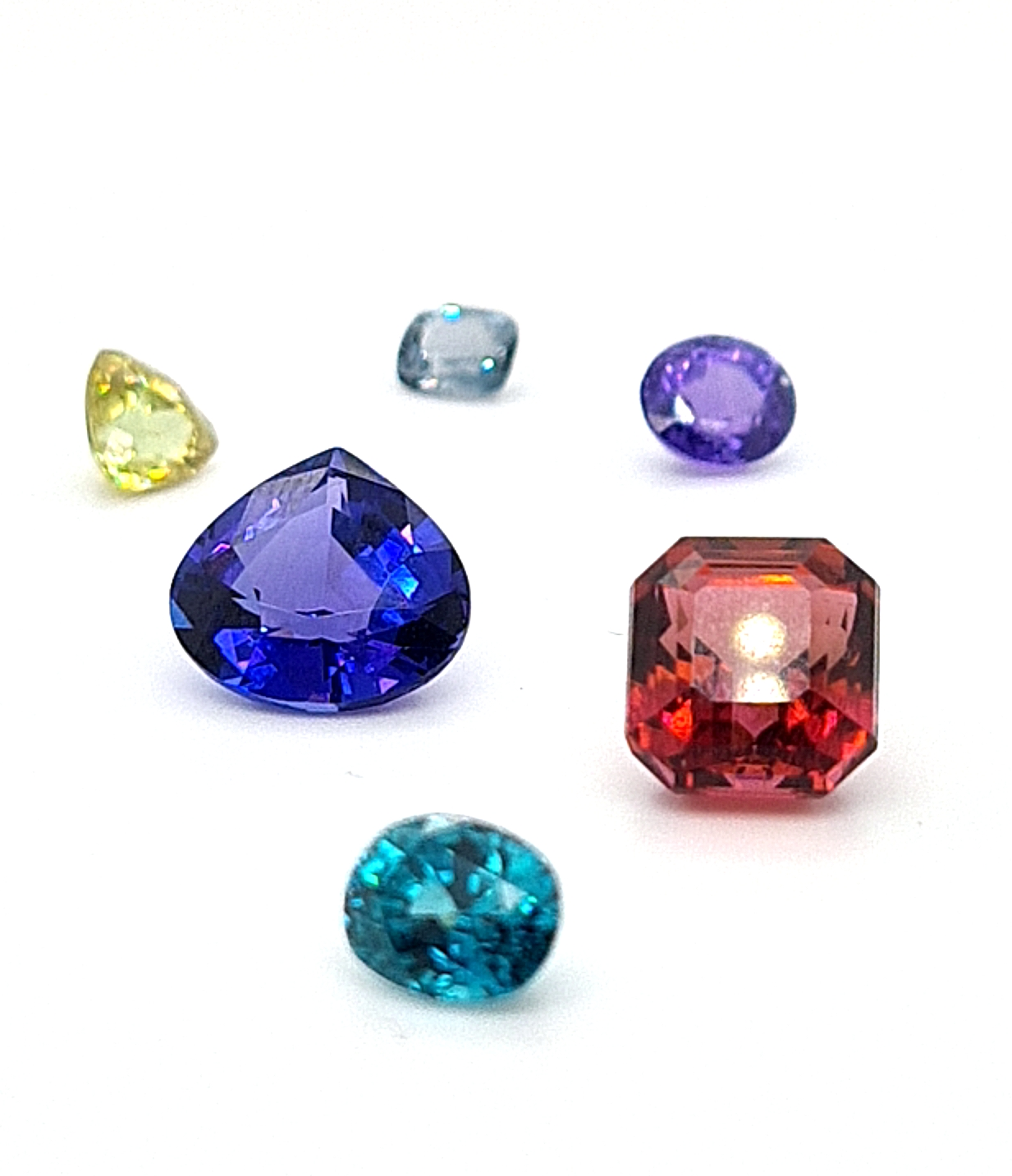 Some stock gems from left to right is sphene, tanzanite, spinel (grey), zircon, sapphire (purple) &amp; tourmaline (raspberry).
