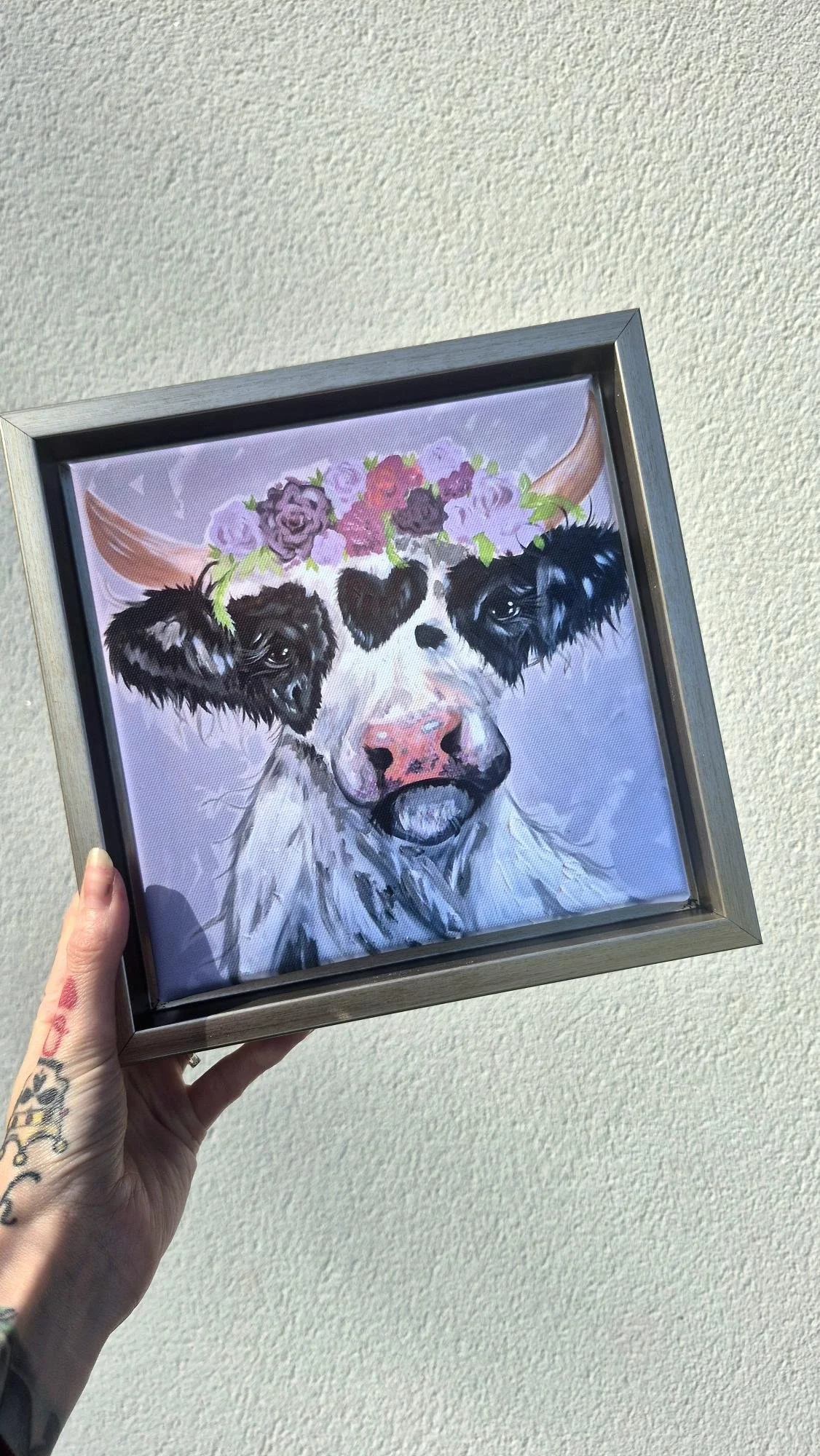 Whimsical framed canvas featuring a black and white cow with a floral crown of pink and purple flowers, rustic animal wall art decor