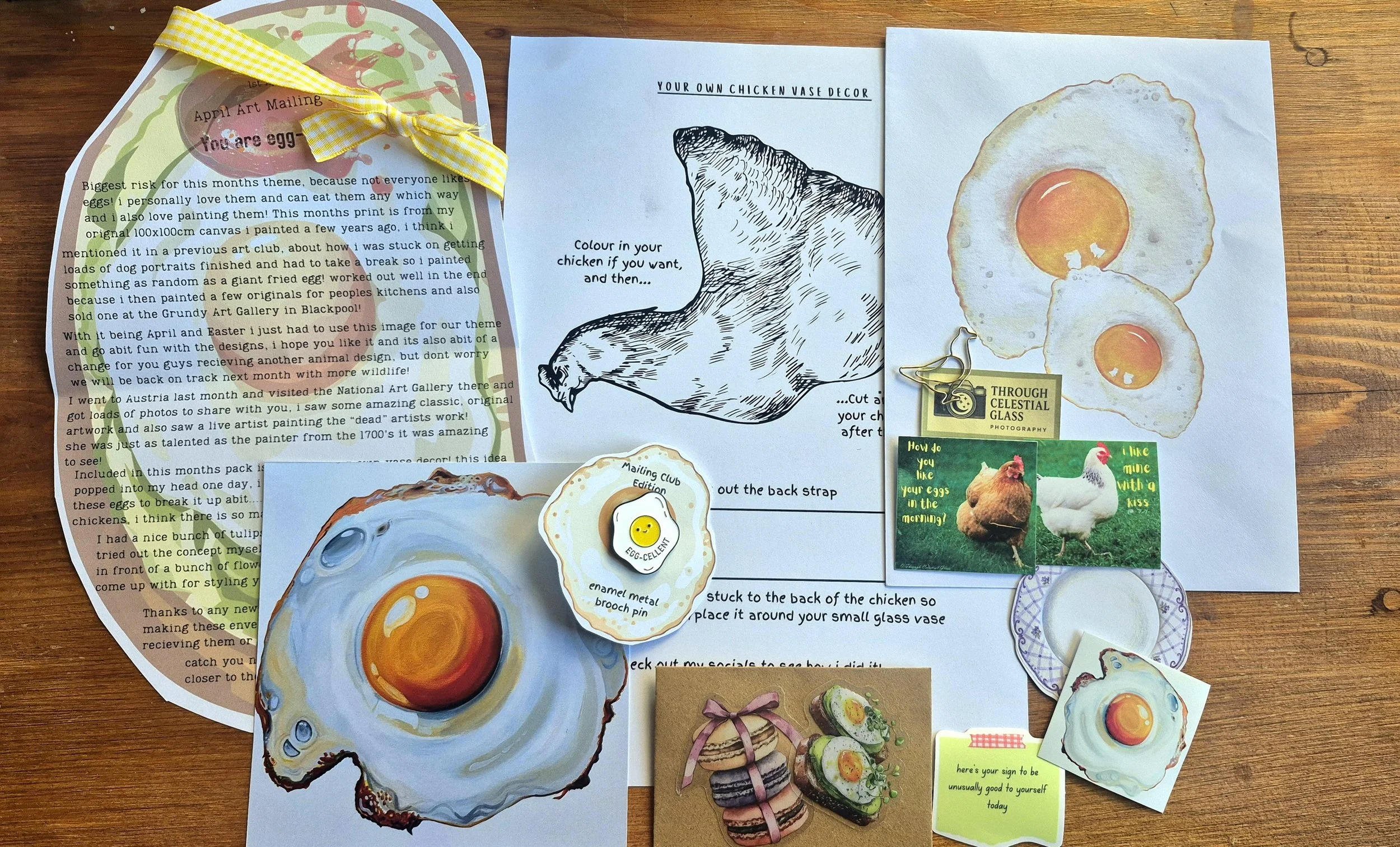 Collection of paper crafts, illustrations, and notes with egg-themed artwork, including painted egg images, a black and white chicken drawing, and various small decorative items on a wooden surface.