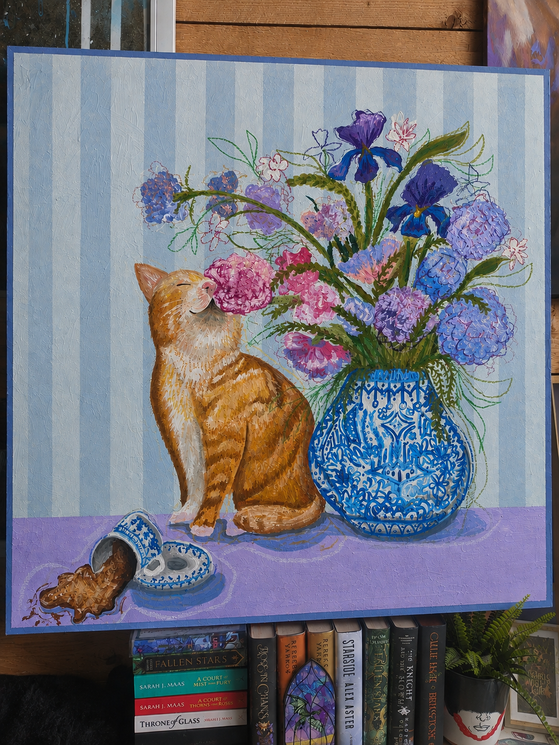 September illustration features a very curious ginger cat sitting beside an overflowing bouquet of pink, lilac and blue flowers, arranged in an ornate blue-and-white patterned vase.