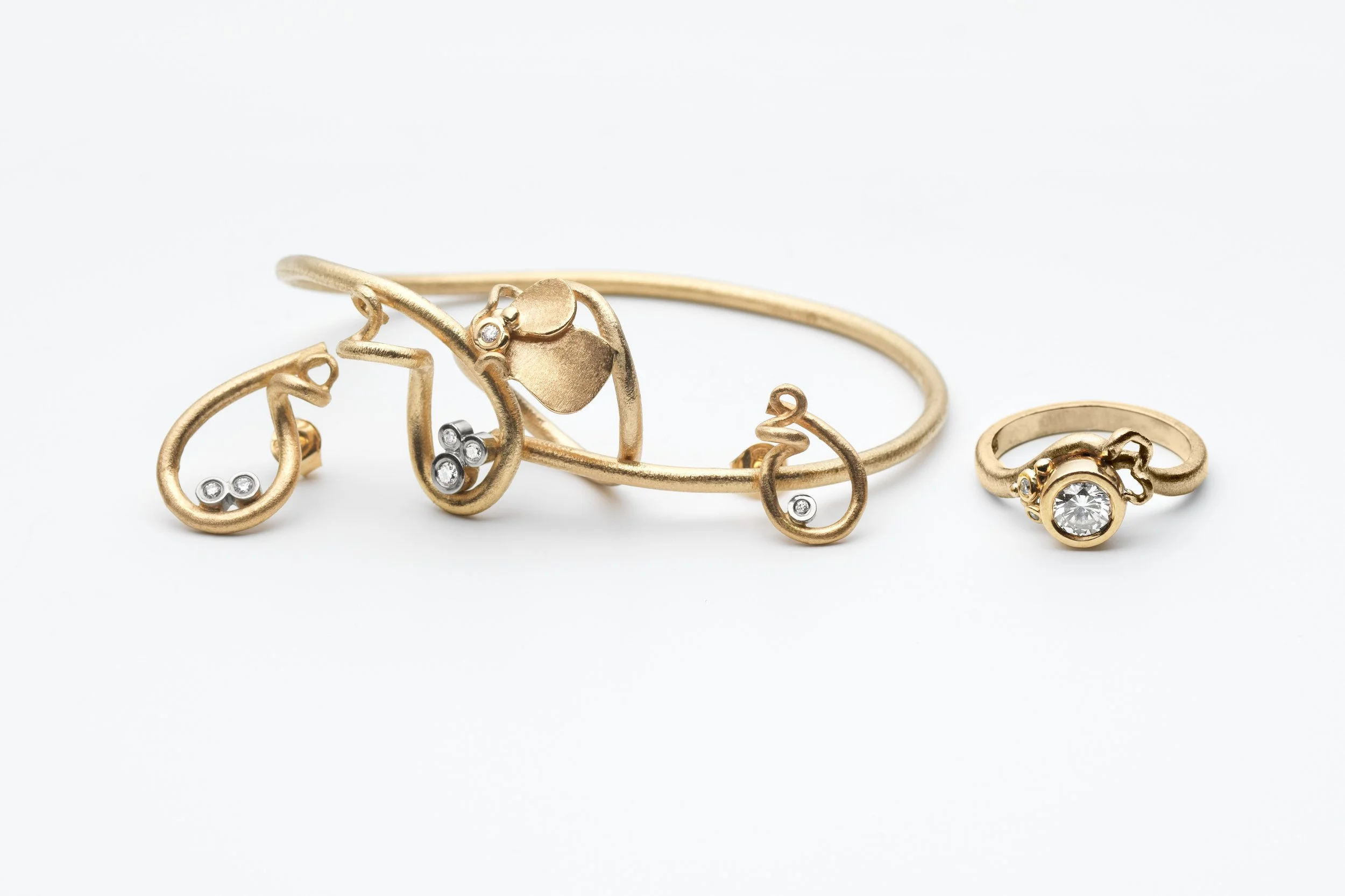 Gold jewelry set including a ring, bracelet, and earrings with embedded gemstones, displayed on a white background.