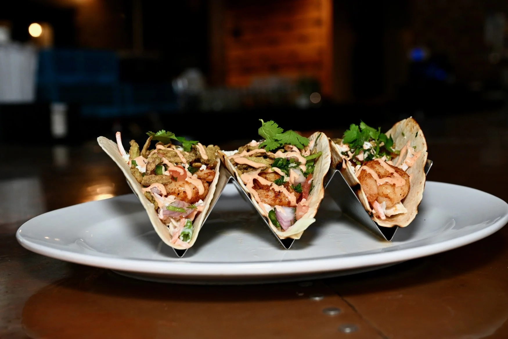 Three Burntwood Tavern street tacos — grilled chicken, blackened shrimp, and baja fish — with pickled slaw, cotija, and crispy jalapeños