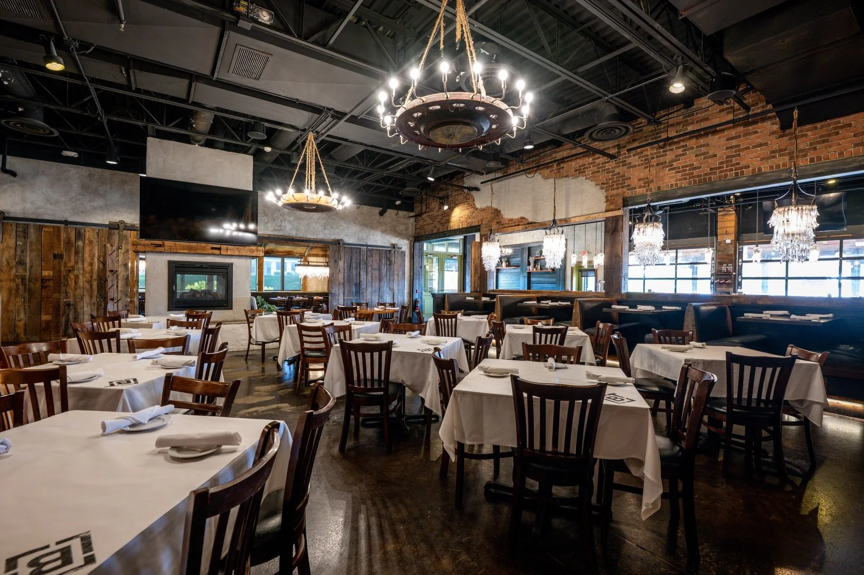 Burntwood Tavern Fairlawn dining room with iron chandeliers, exposed brick walls, and reclaimed wood beams