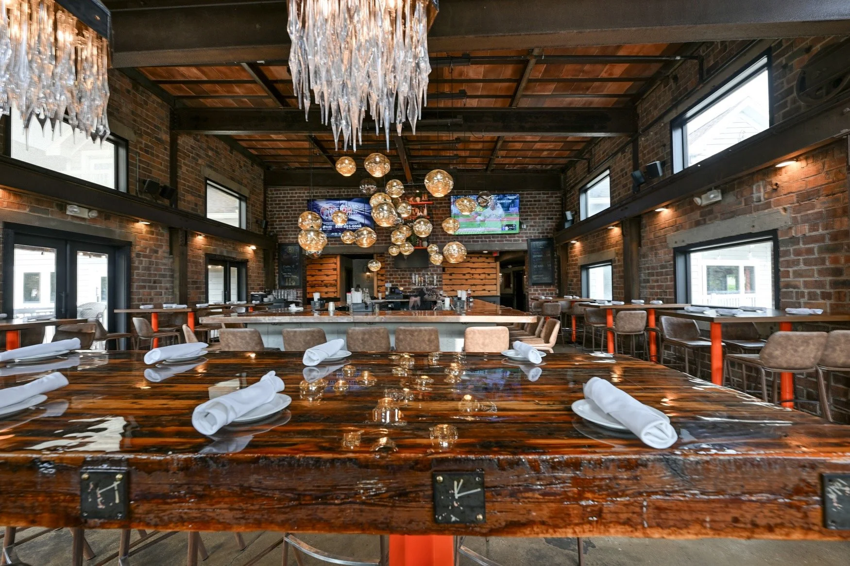 Burntwood Tavern Cuyahoga Falls bar area with copper topped bar, hand-blown chandelier, and harvest table