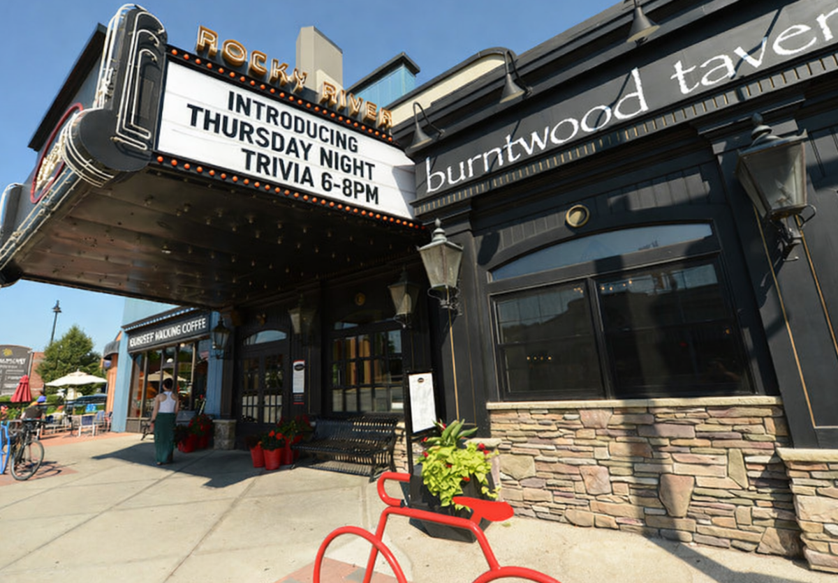 Burntwood Tavern Rocky River exterior on Detroit Road at dusk, featuring the original Beachcliff Theatre marquee, warm lighting, and sidewalk seating