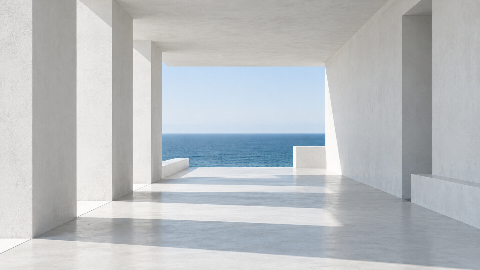 A white architectural corridor opening toward a blue sea