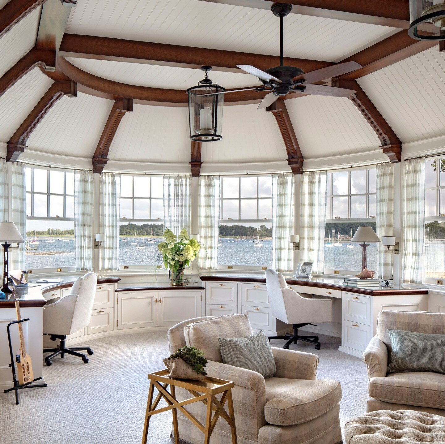 The nautically-themed home office in this 'New England Shingle Style Residence' features built-in desks with panoramic views overlooking Long Island Sound.  Mahogany beams support a radiating beadboard ceiling.⁠ #officewithaview #roomwithaview⁠
⁠
Arc