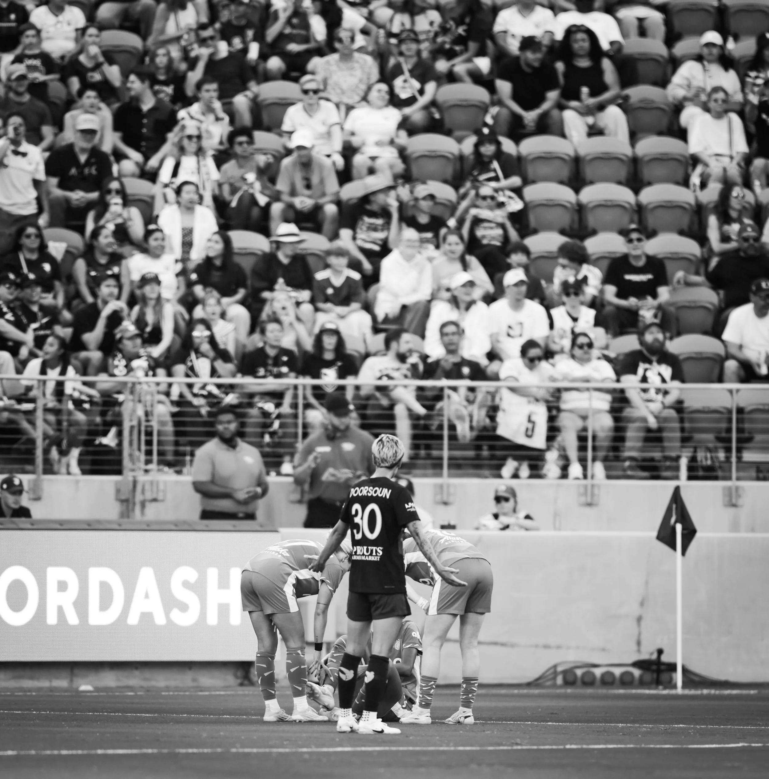 A soccer game in a stadium with players on the field and spectators watching from the stands.
