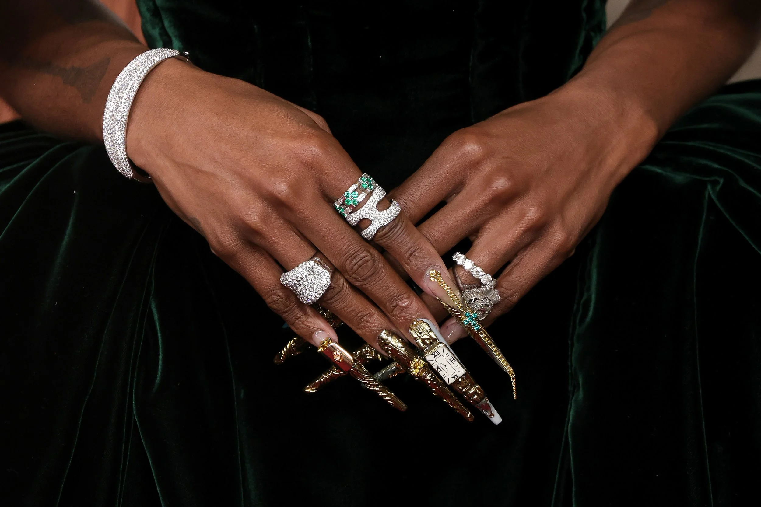 Close-up of a person's hands adorned with various jewelry including rings, bracelets, and a watch, showcasing a mix of silver, gold, and gemstone pieces.