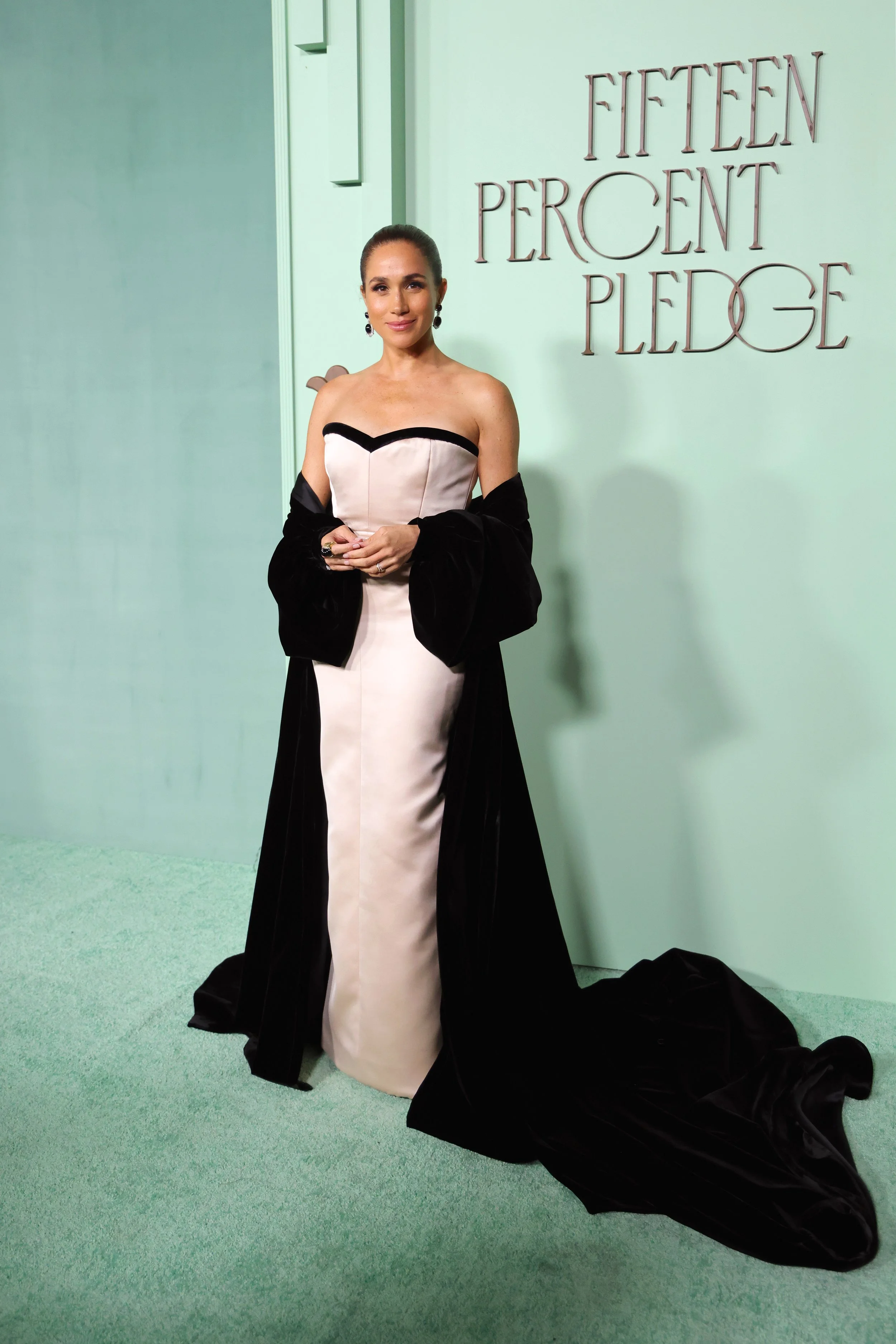 Lady in an elegant gown standing in front of a backdrop with the words "Fifteen Percent Pledge"