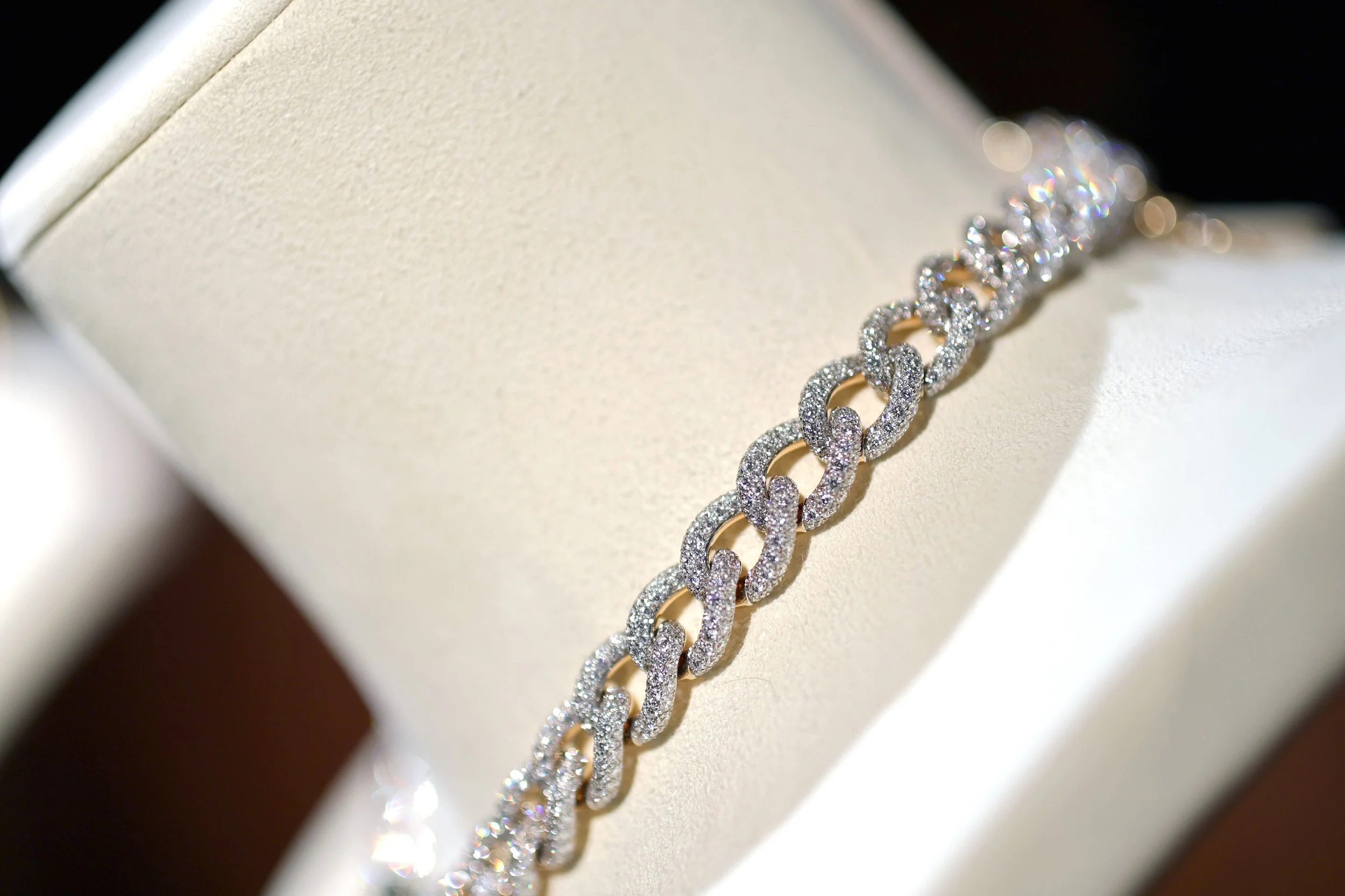 A diamond-encrusted chain bracelet displayed on a white jewelry box.