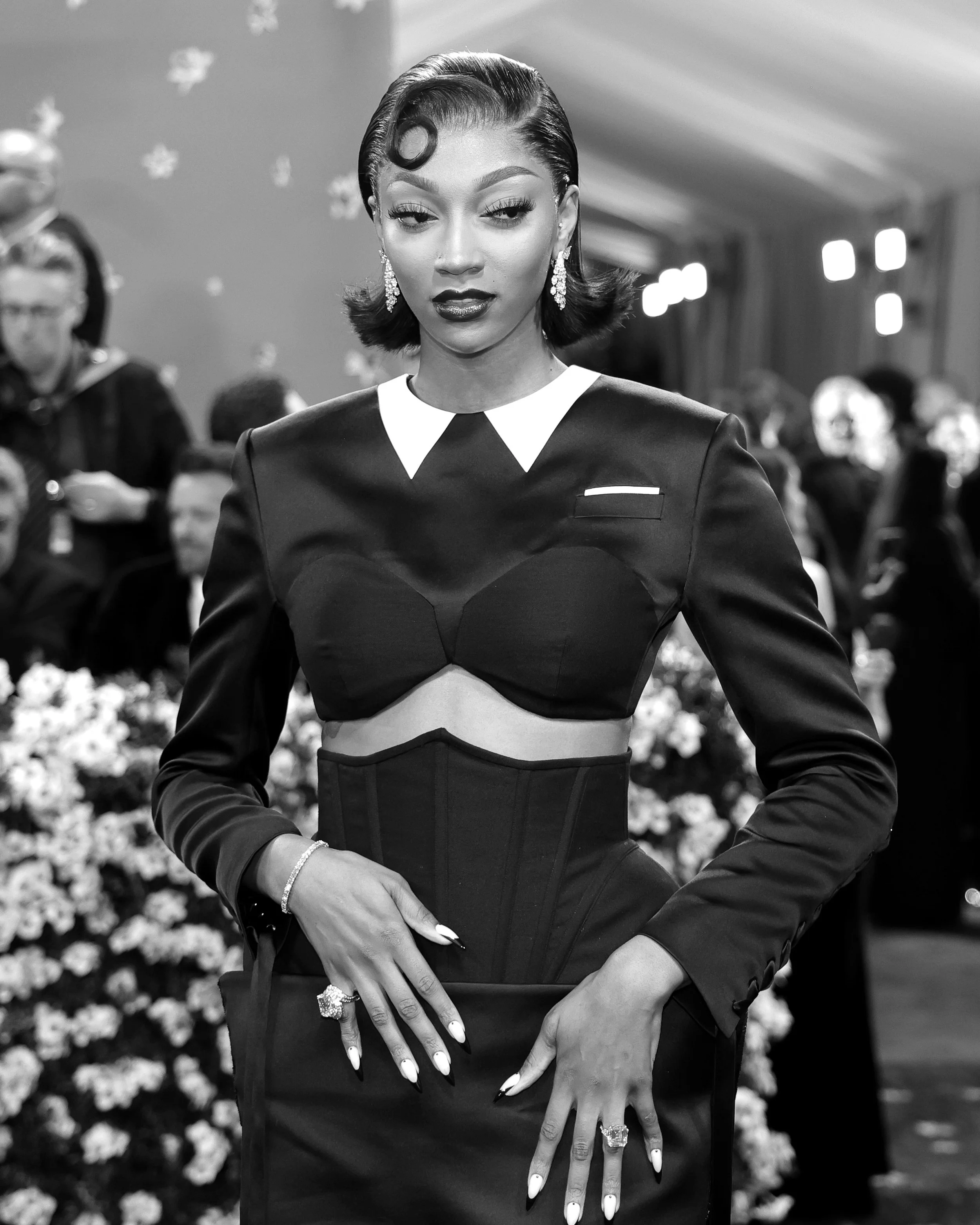 A woman in a black dress with white accents and jewelry, posing at a formal event.