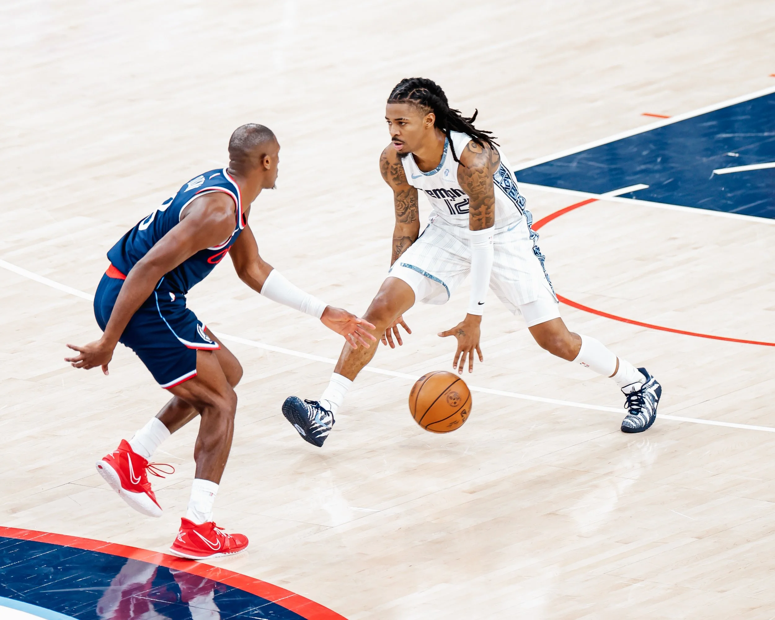 Two basketball players, one in a blue uniform and the other in white, competing for the ball on the court.