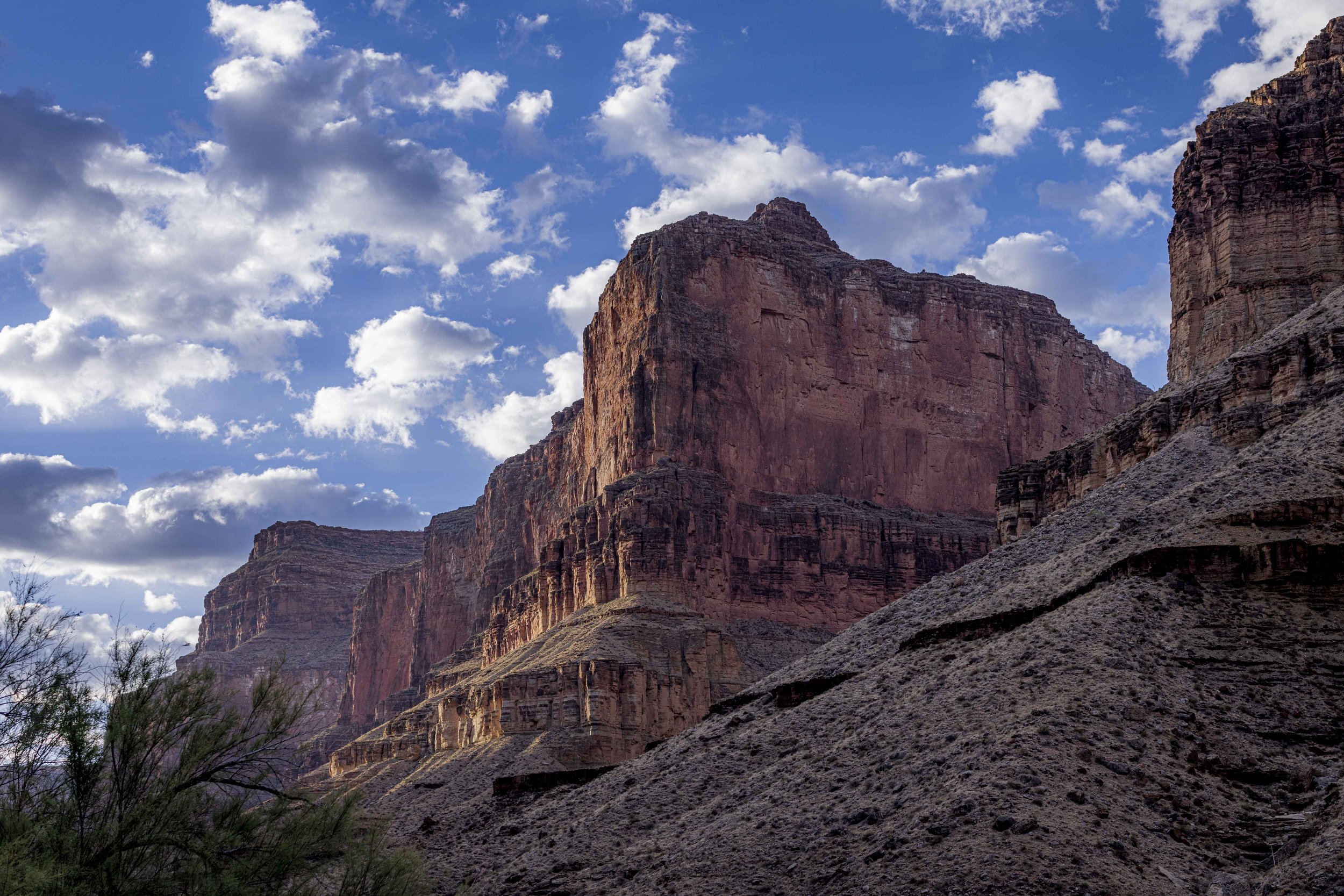 View of towering red and brown canyon cliffs under a partly cloudy sky in the Grand Canyon.