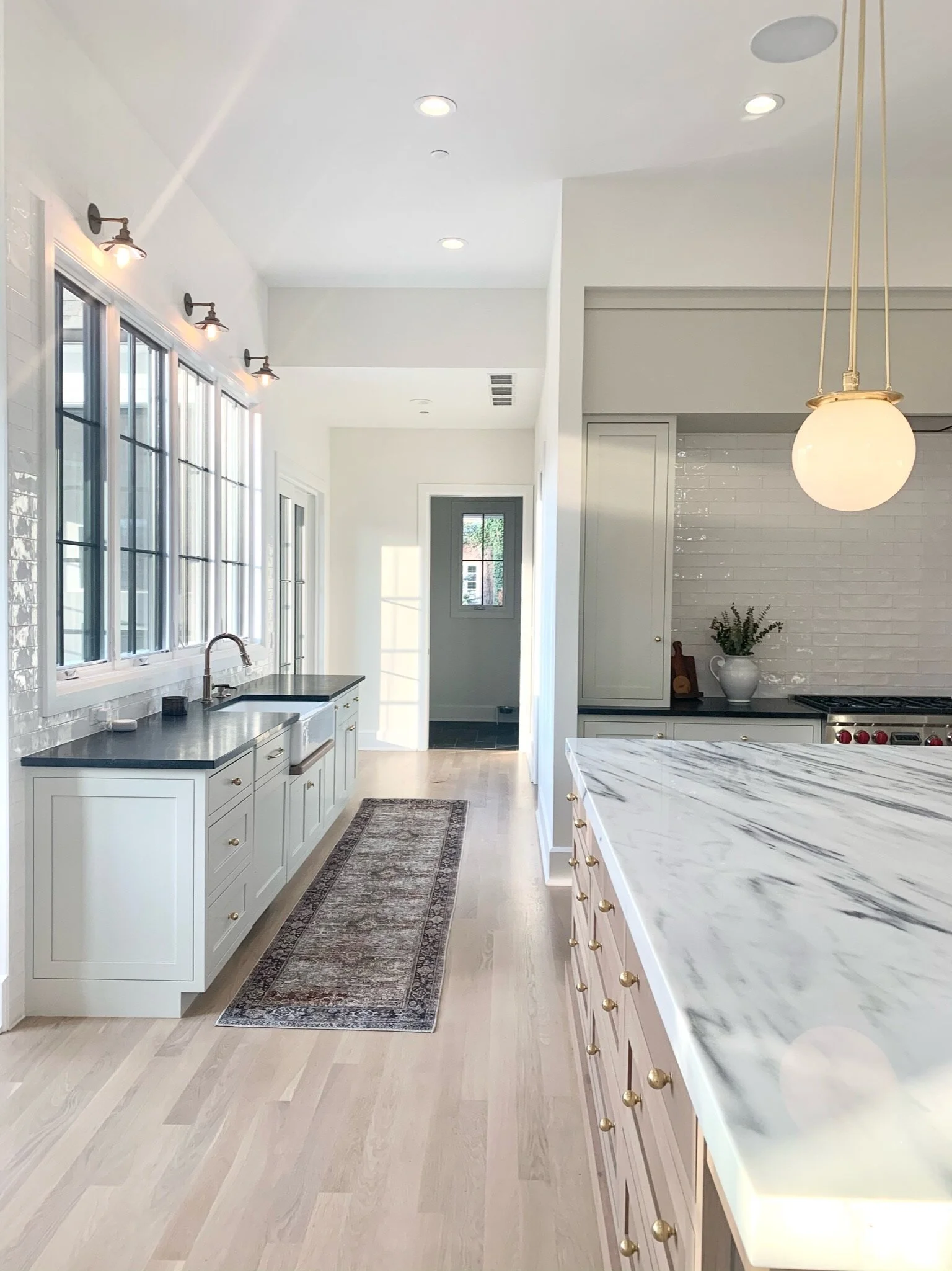 ArtesianDesigns_ kitchen sedate gray cabinets white marble counters honed silk granite drip ledge mirrored cabinets white oak island bistro globes loloi runner