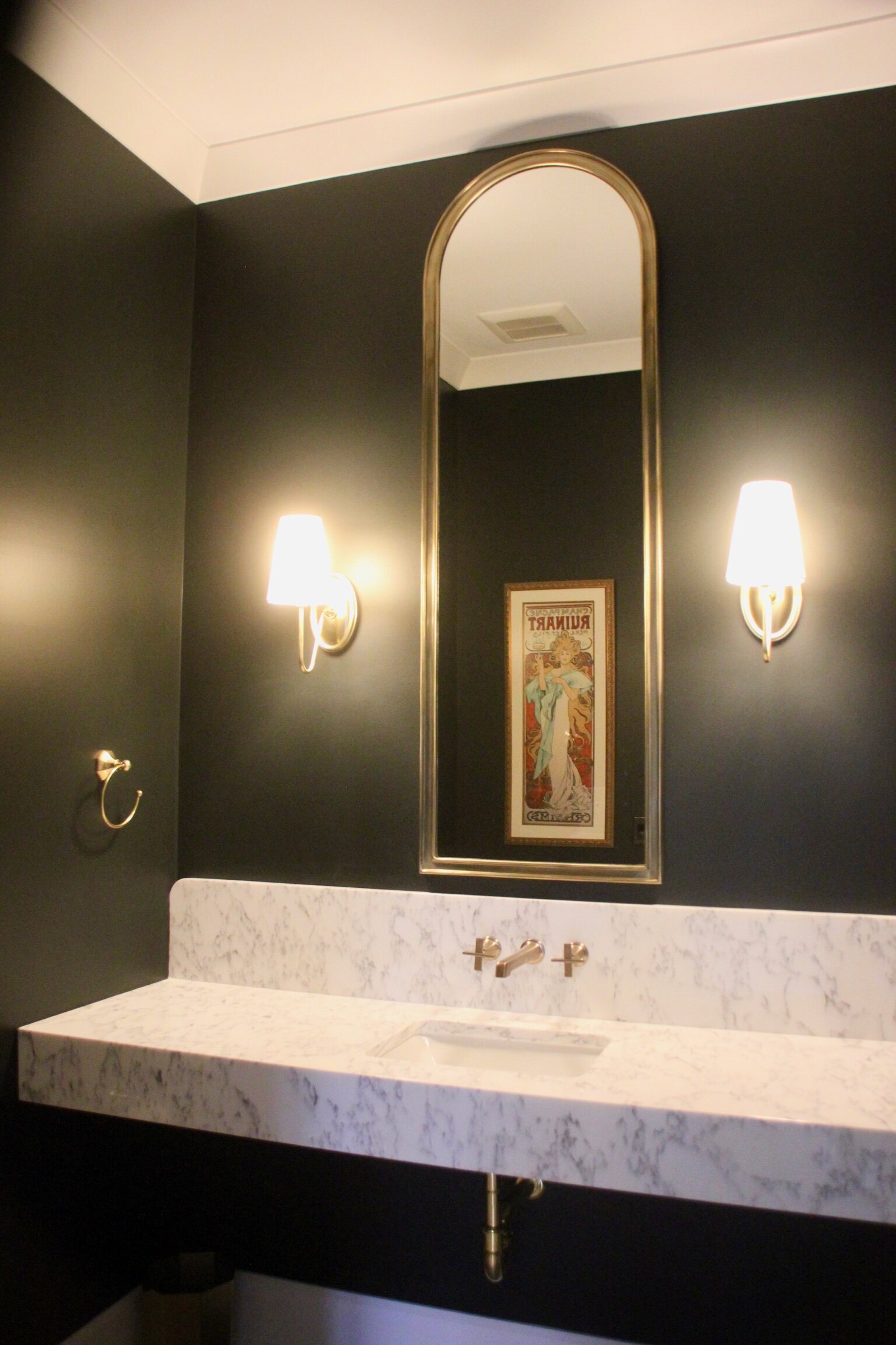 ArtesianDesigns_ Moody Powder Room with floating marble vanity arched gold mirror and brass fixtures rejuvenation berkshire sconce