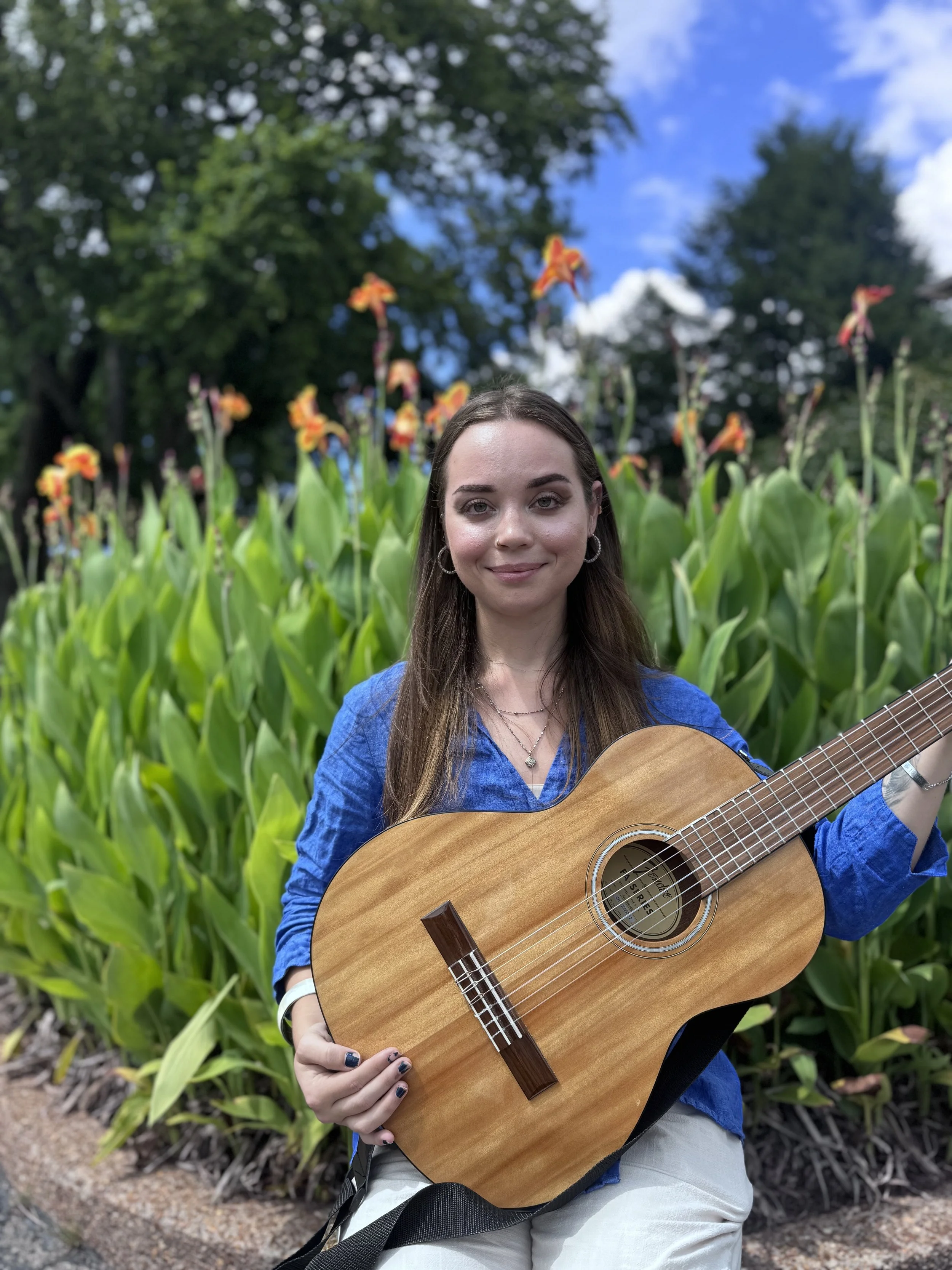 girl with brown hair blue shirt and a guitar