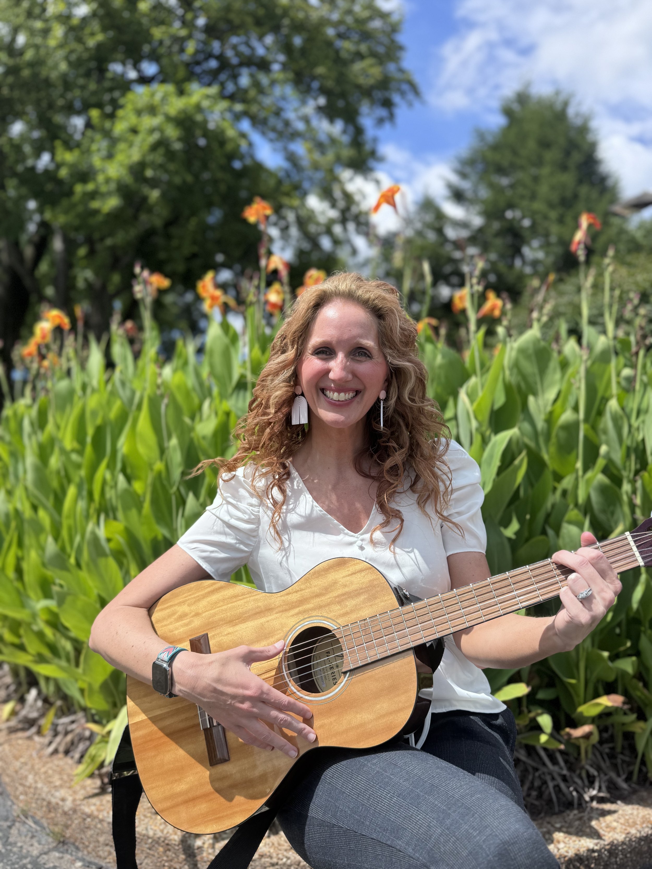 Girl with brown curly hair holding a guitar