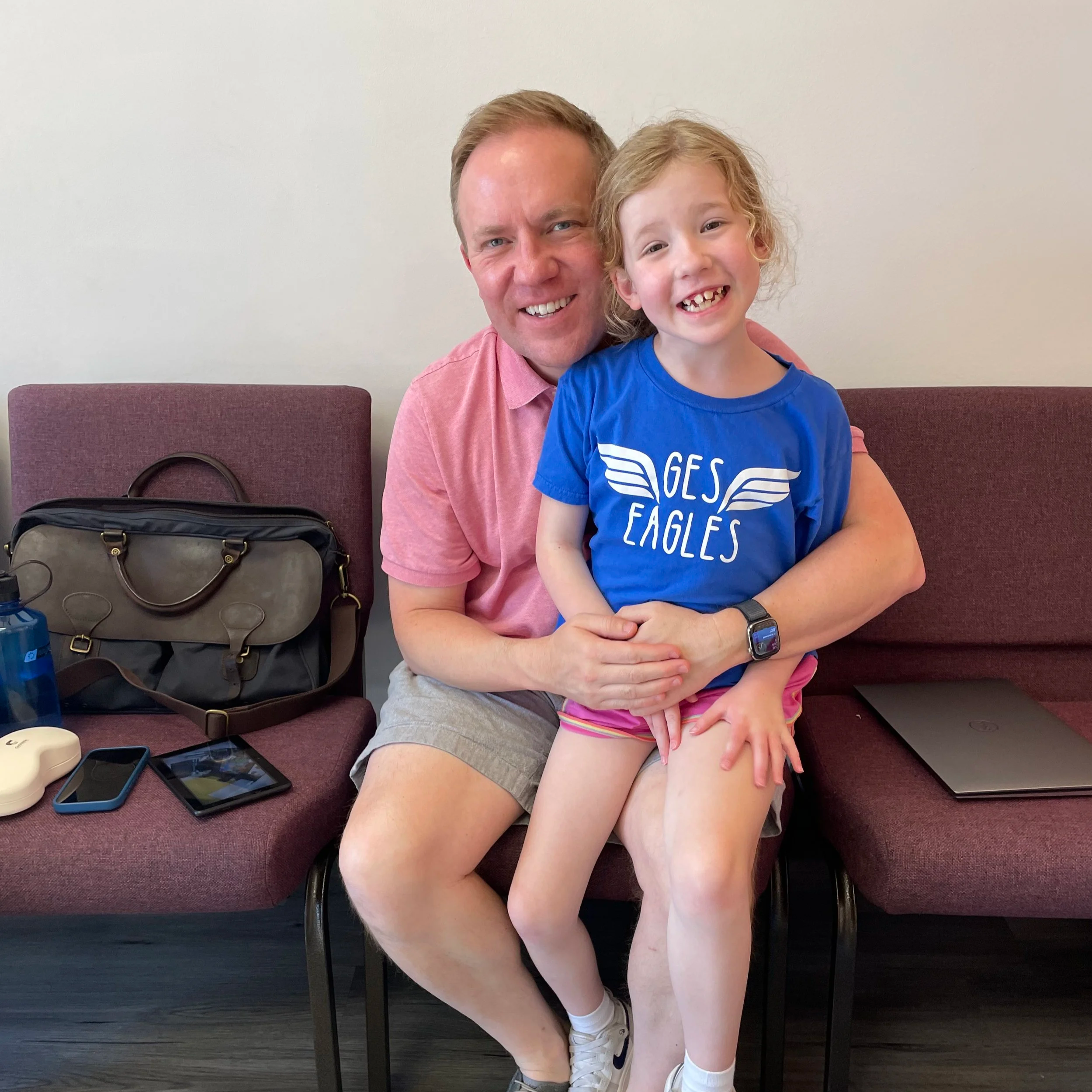 young blond girl seated on her father's lap after therapy session