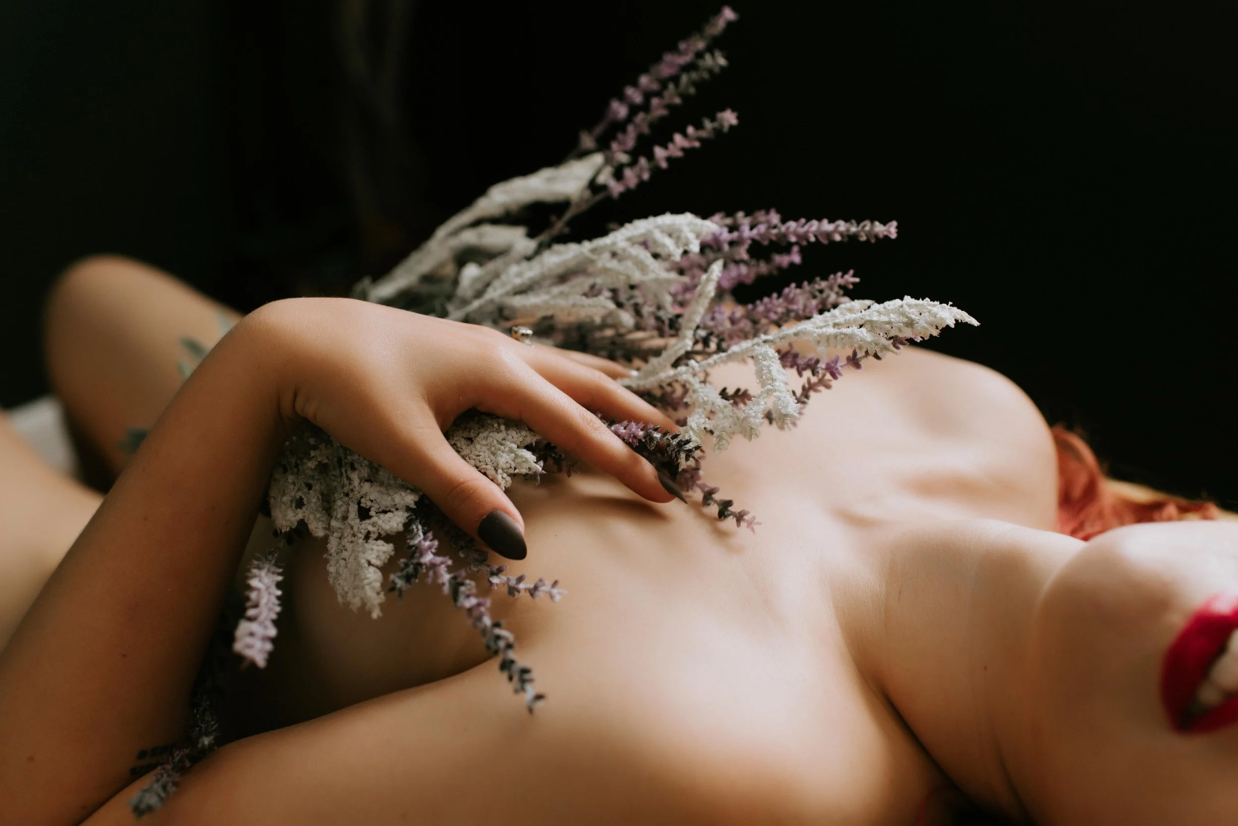 Nude boudoir client with wildflowers on her chest