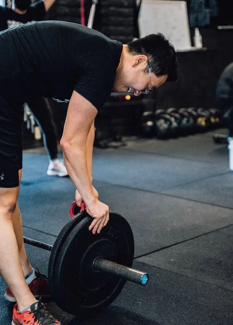 Athlete loading a bumper plate onto a barbell at Tech City Fit in Sunnyvale, CA