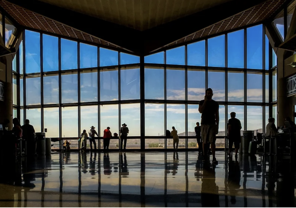 Travelers inside an airport terminal overlooking the runway, representing business travel planning, flight coordination, and personalized travel services.