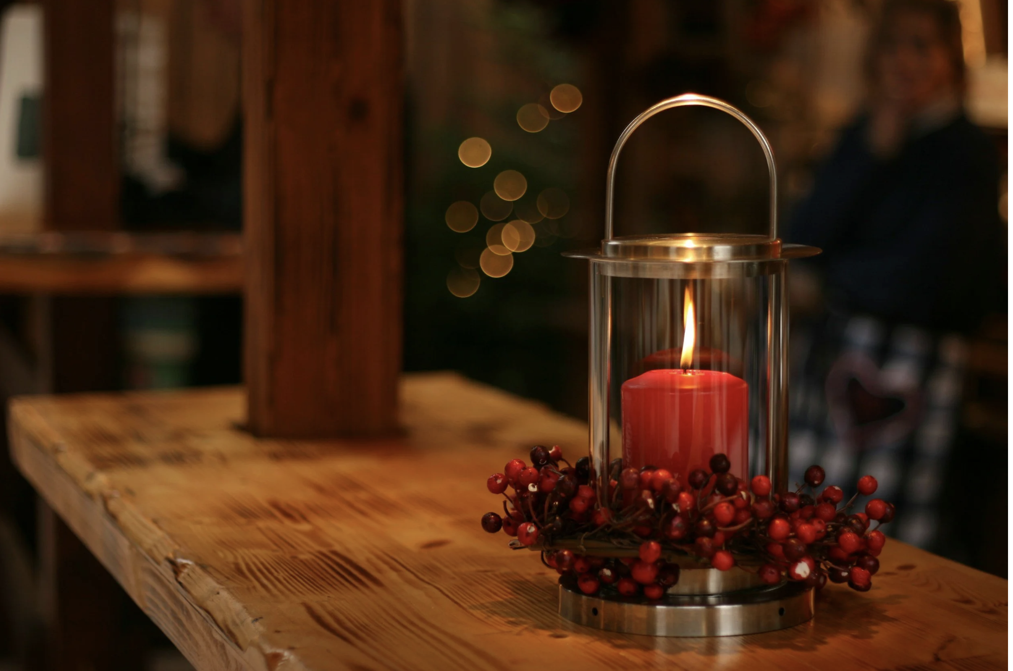 Red candle in a lantern with festive holiday décor, representing the Christmas season and planning holiday travel in advance.