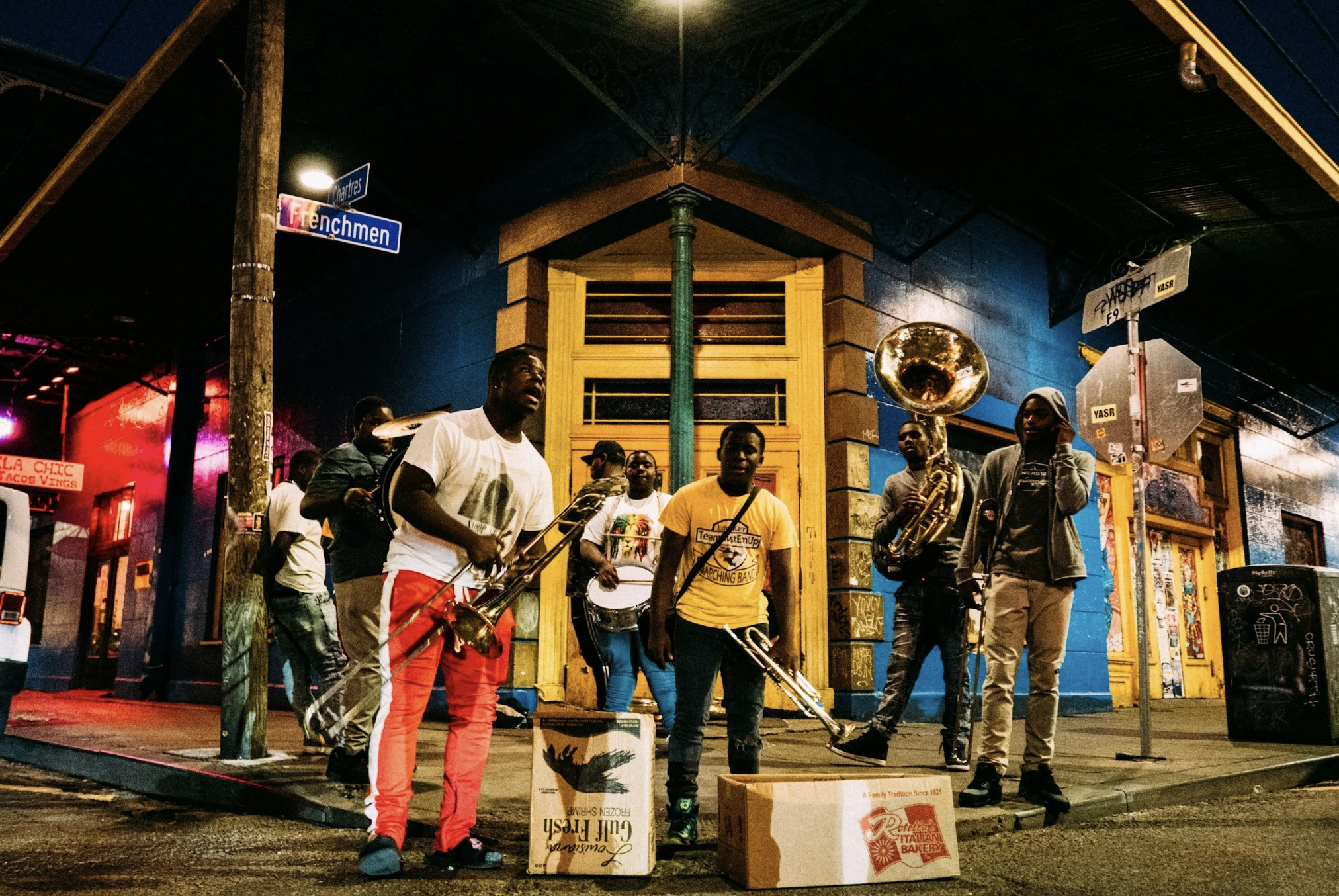 Brass band performing live on a street corner in the French Quarter of New Orleans at night.