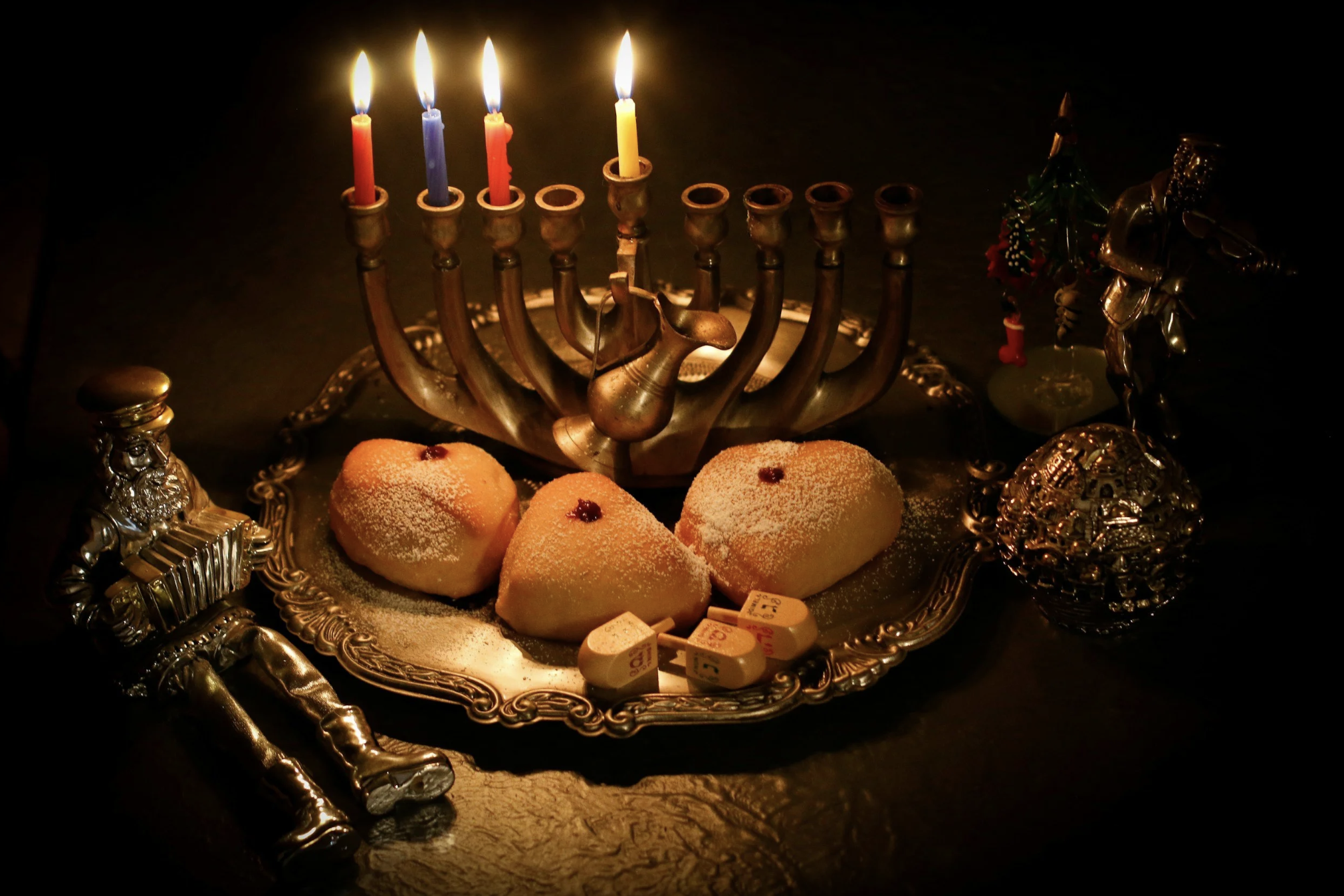 Lit Hanukkah menorah with traditional holiday treats, representing Hanukkah celebrations during the holiday travel season.
