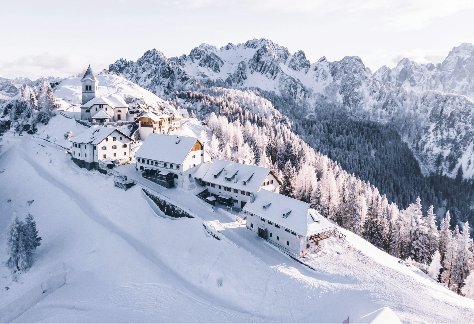 Snow-covered mountain village surrounded by snowy peaks, representing a scenic winter and Christmas holiday getaway.