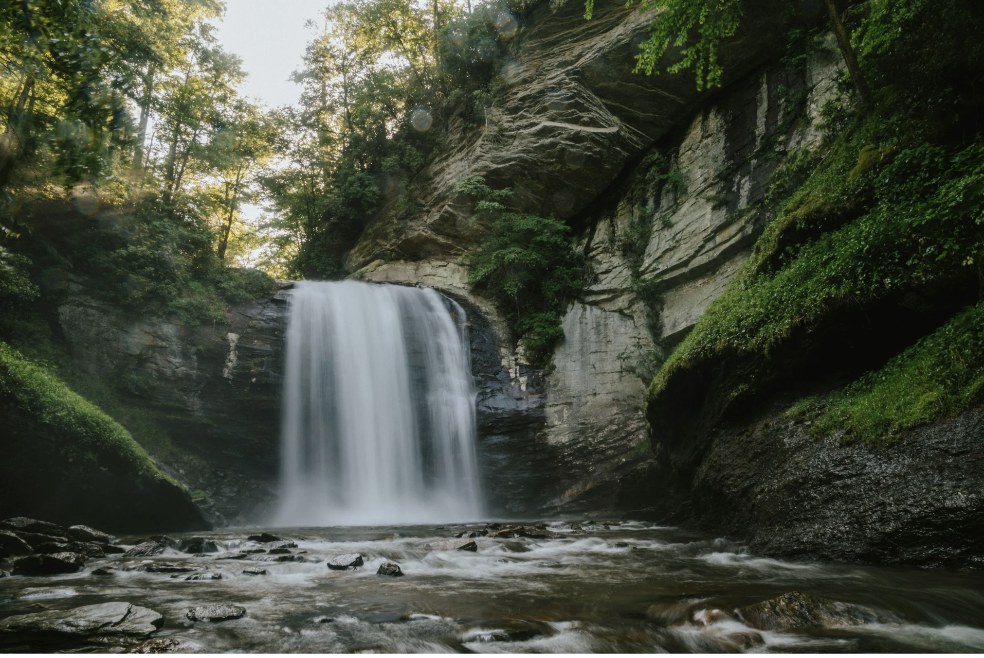 Waterfall flowing through a lush forest and rocky landscape near Asheville, North Carolina.