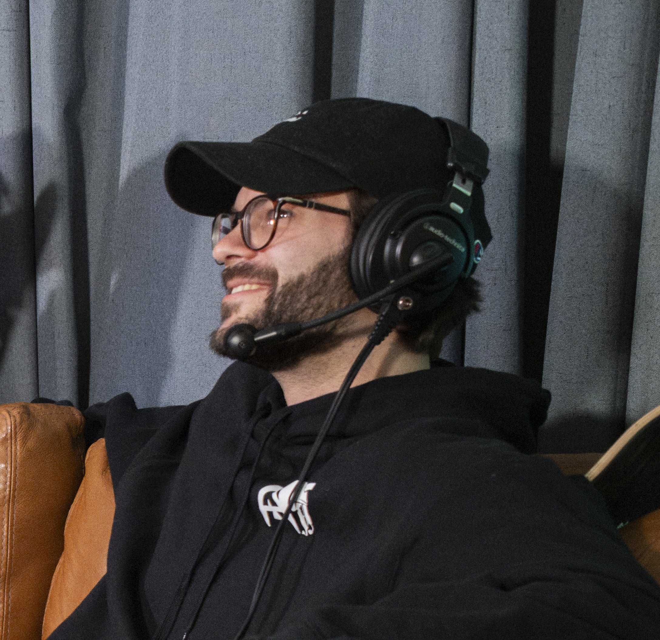A man stands on stairs next to a large sign reading 'REMEMBER' in bold letters, wearing a black hoodie.