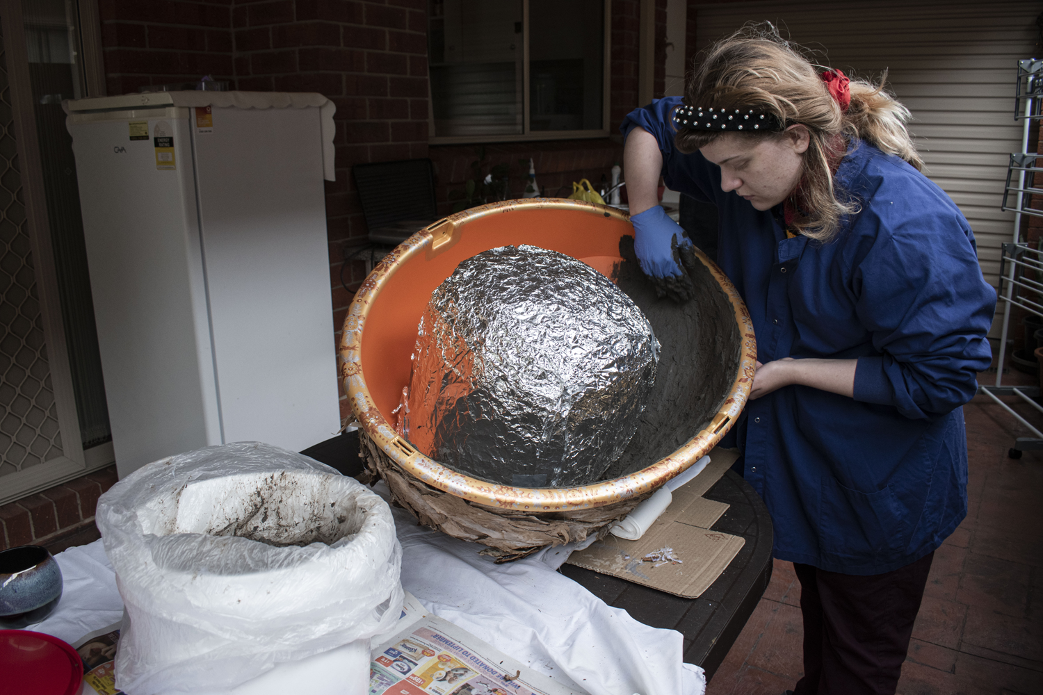making process of sculpture by lathering clay/soil mixture on work. 