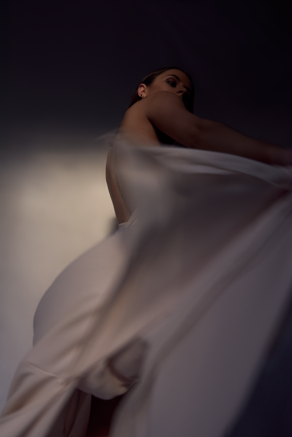 Woman creating movement with her dress highlighted by partial lighting.
