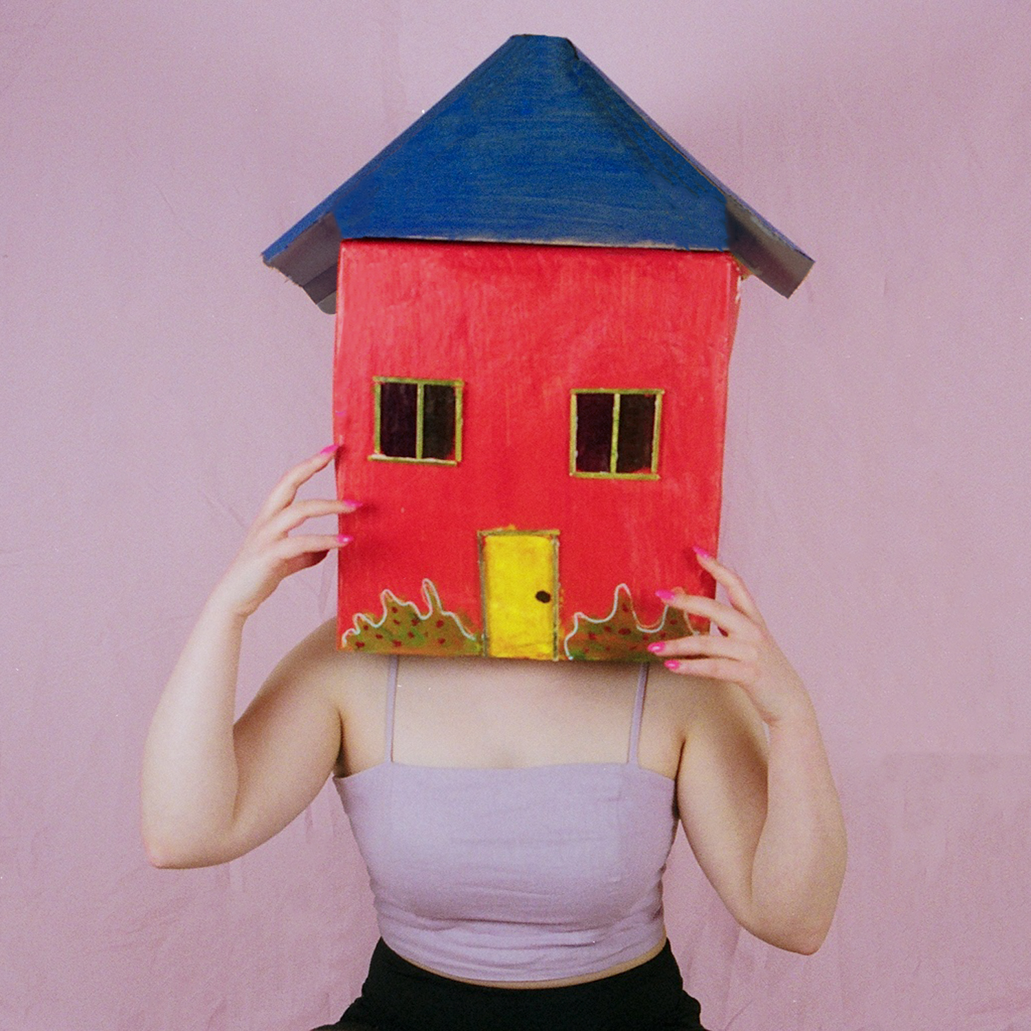 Colour photograph depicting woman with cardboard house over her head.
