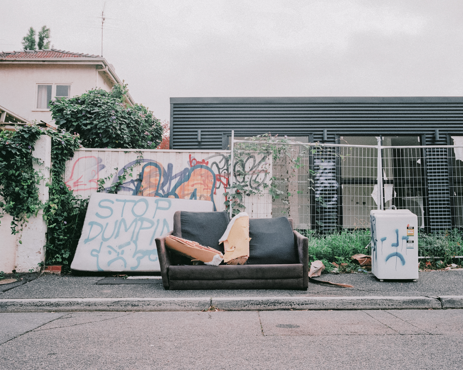 Colour photograph depicting a destroyed couch left on footpath.