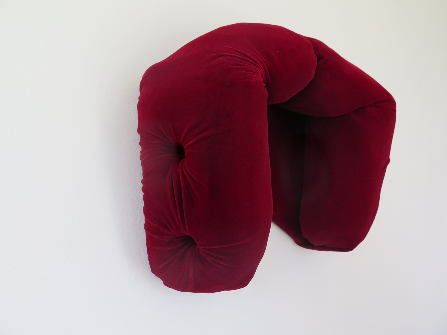 A soft sculptural work, that hangs on the wall. It is a padded sculpture that you can position your face inside of. 