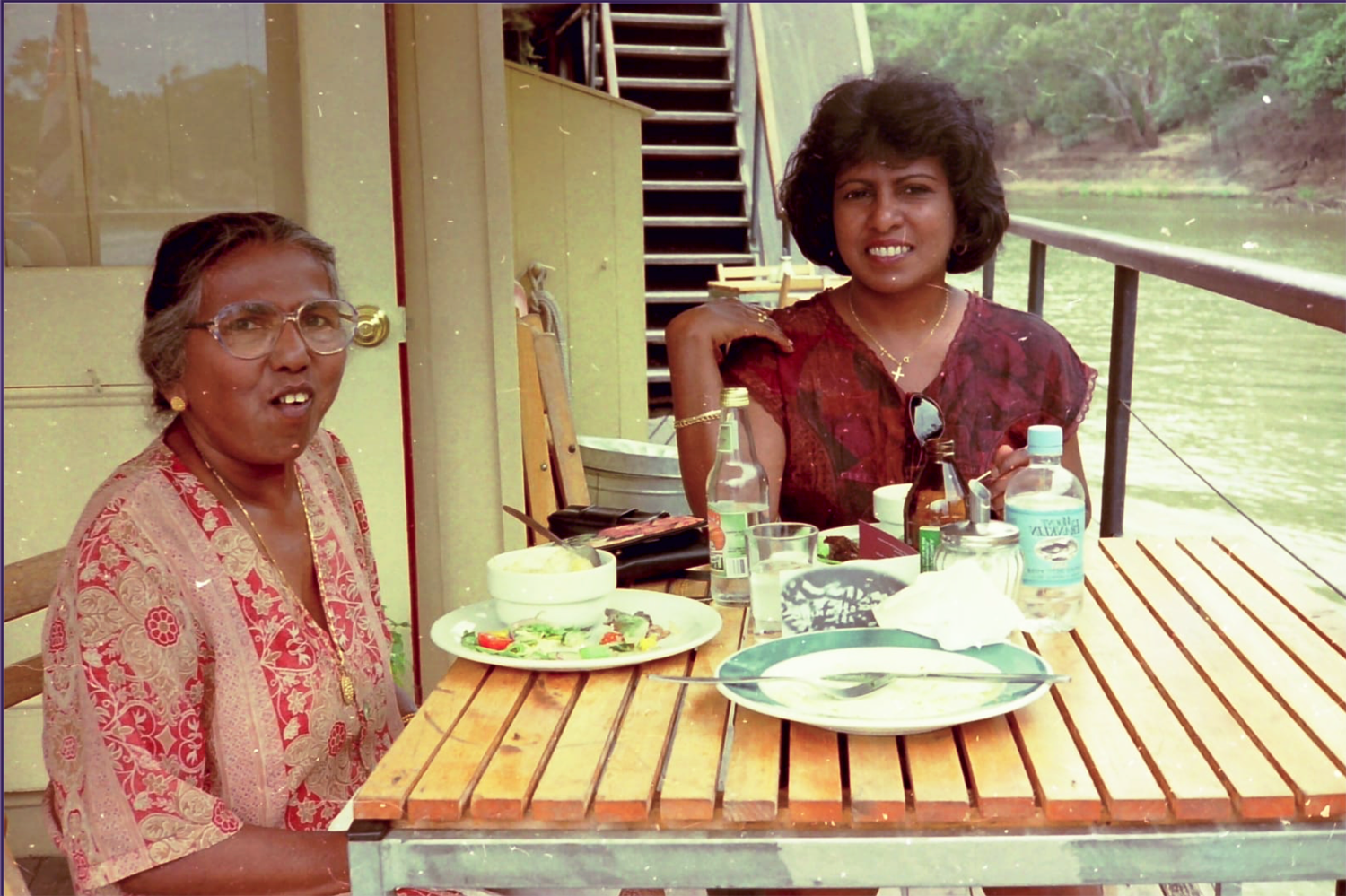 Analogue photograph of two women sitting at a table eating a meal.