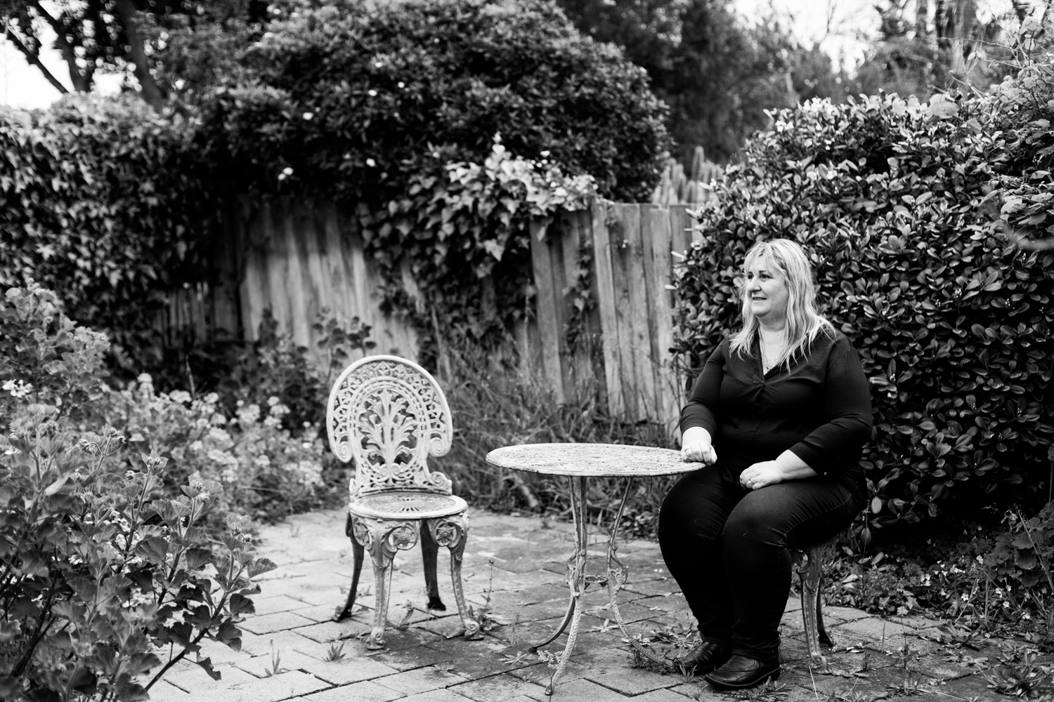 Black and white photograph of woman sitting in suburban backyard. 