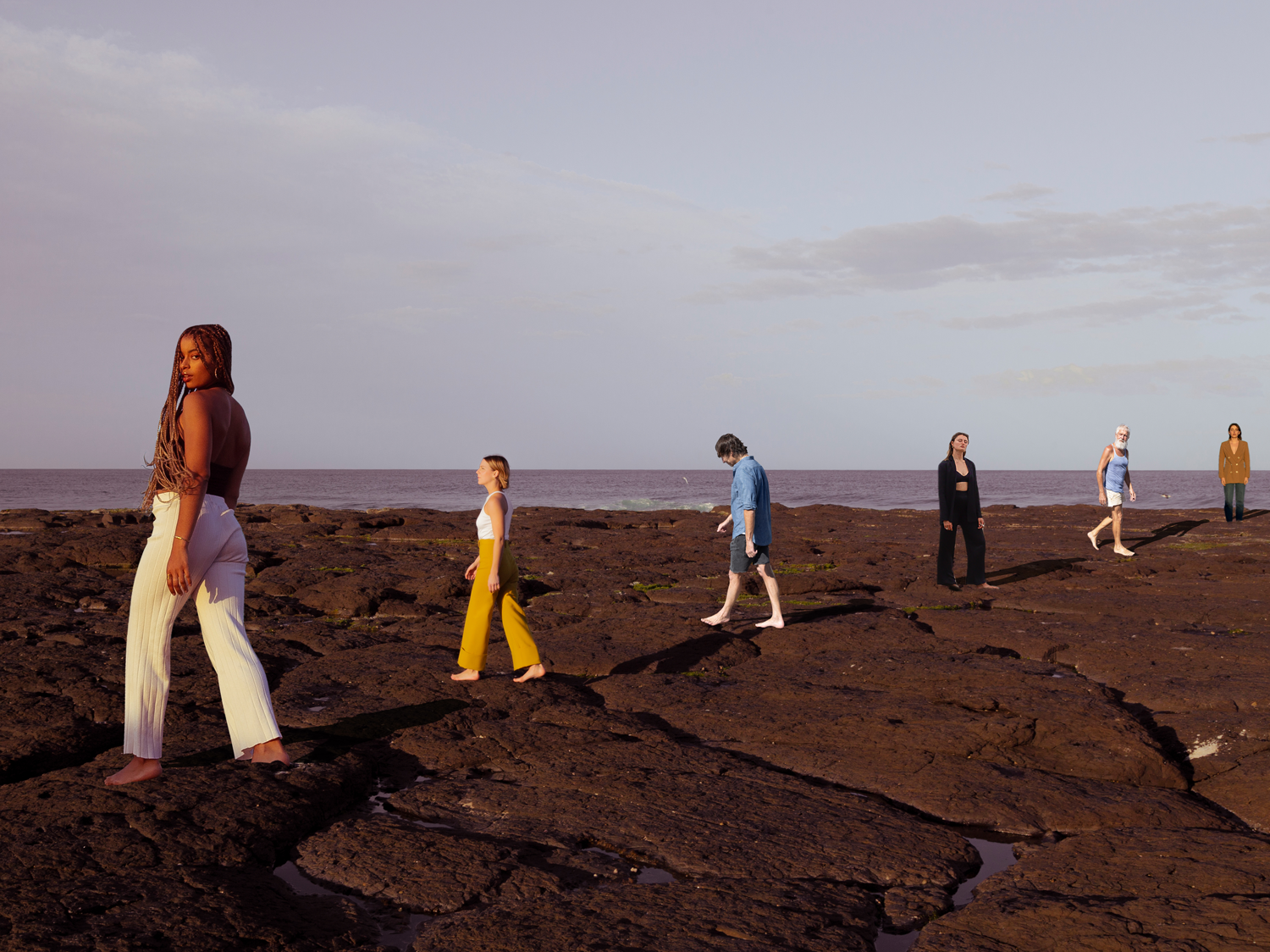 Colour image of six people standing on varied rock formations at a shore line. Ocean can be seen in background.