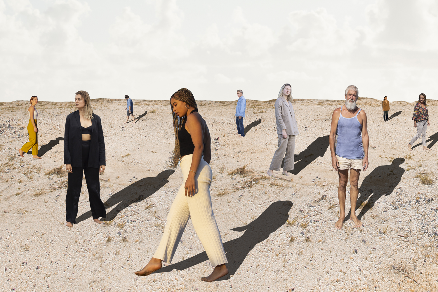 Colour photograph of nine people standing in a sandy landscape.