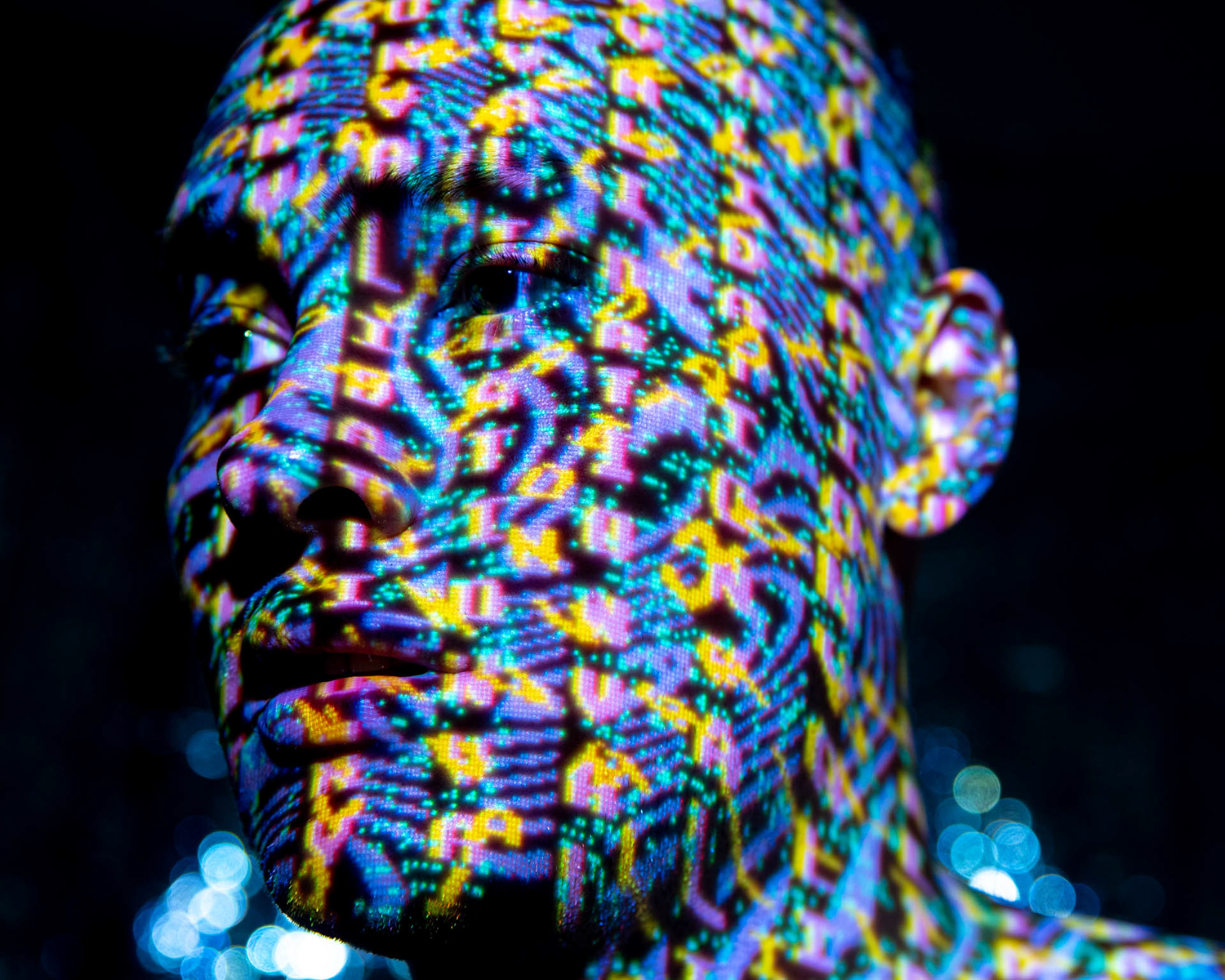 Colour image of a portrait of a man with projected digital imagery covering his face. 