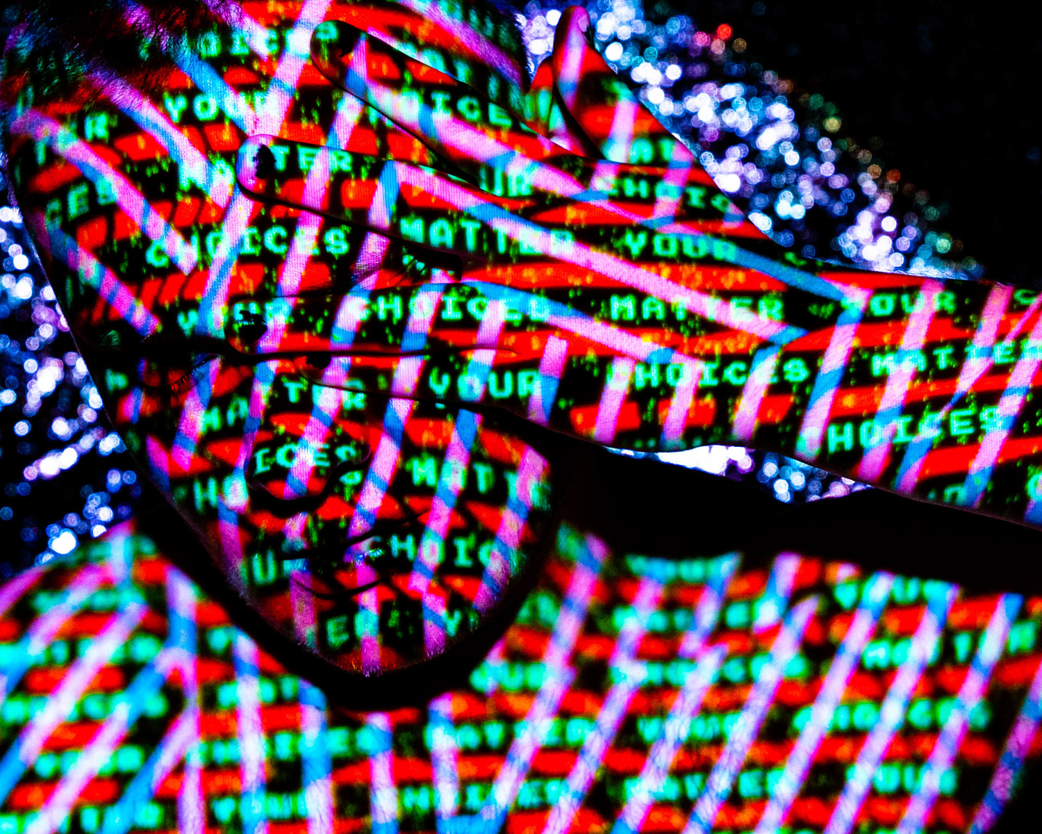Colour image of a portrait of a man with projected digital imagery covering his face. The words "your choices matter" are displayed on his skin.